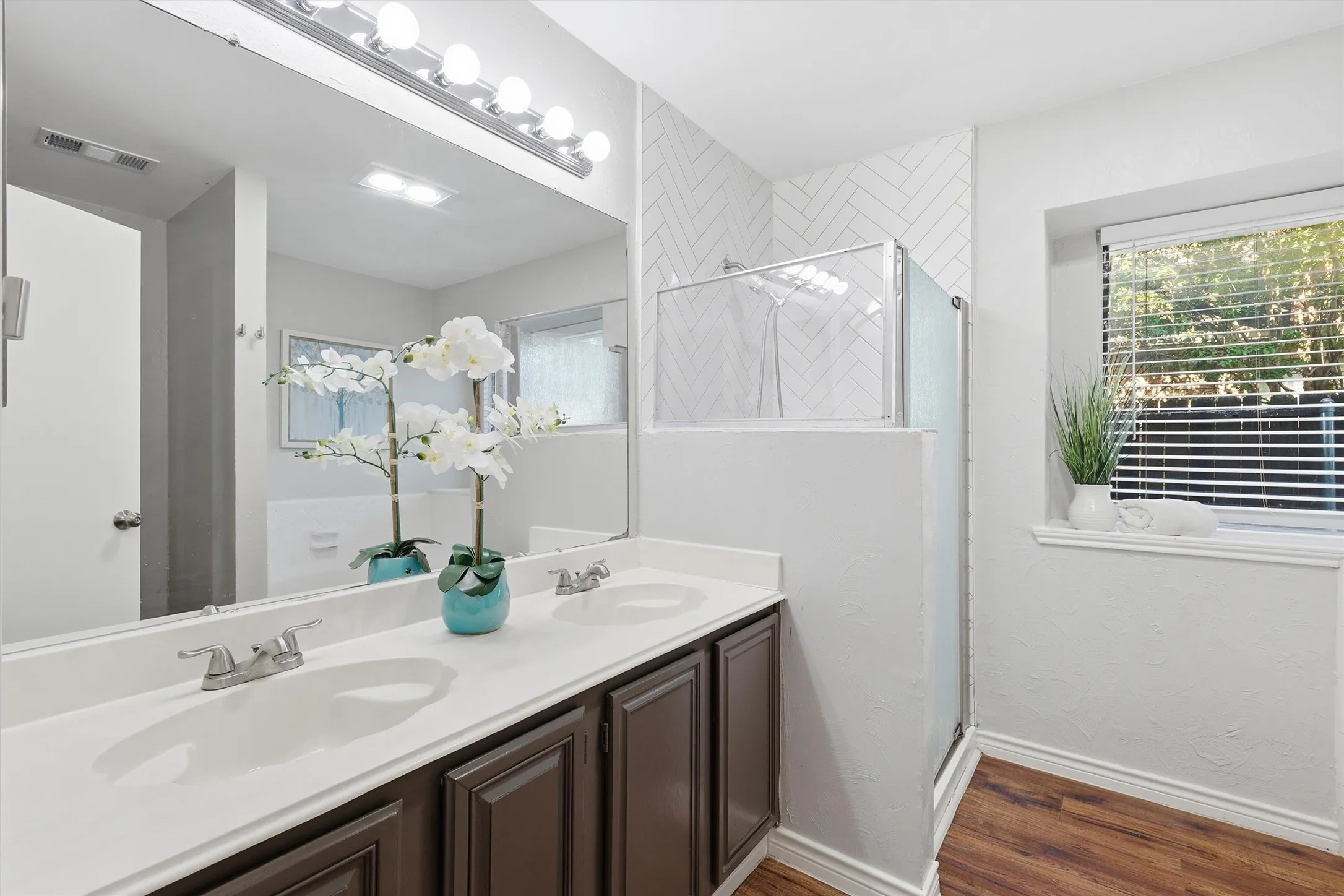 Bathroom featuring a dual vanity with white countertops, dark wood-finish cabinetry, and chrome fixtures