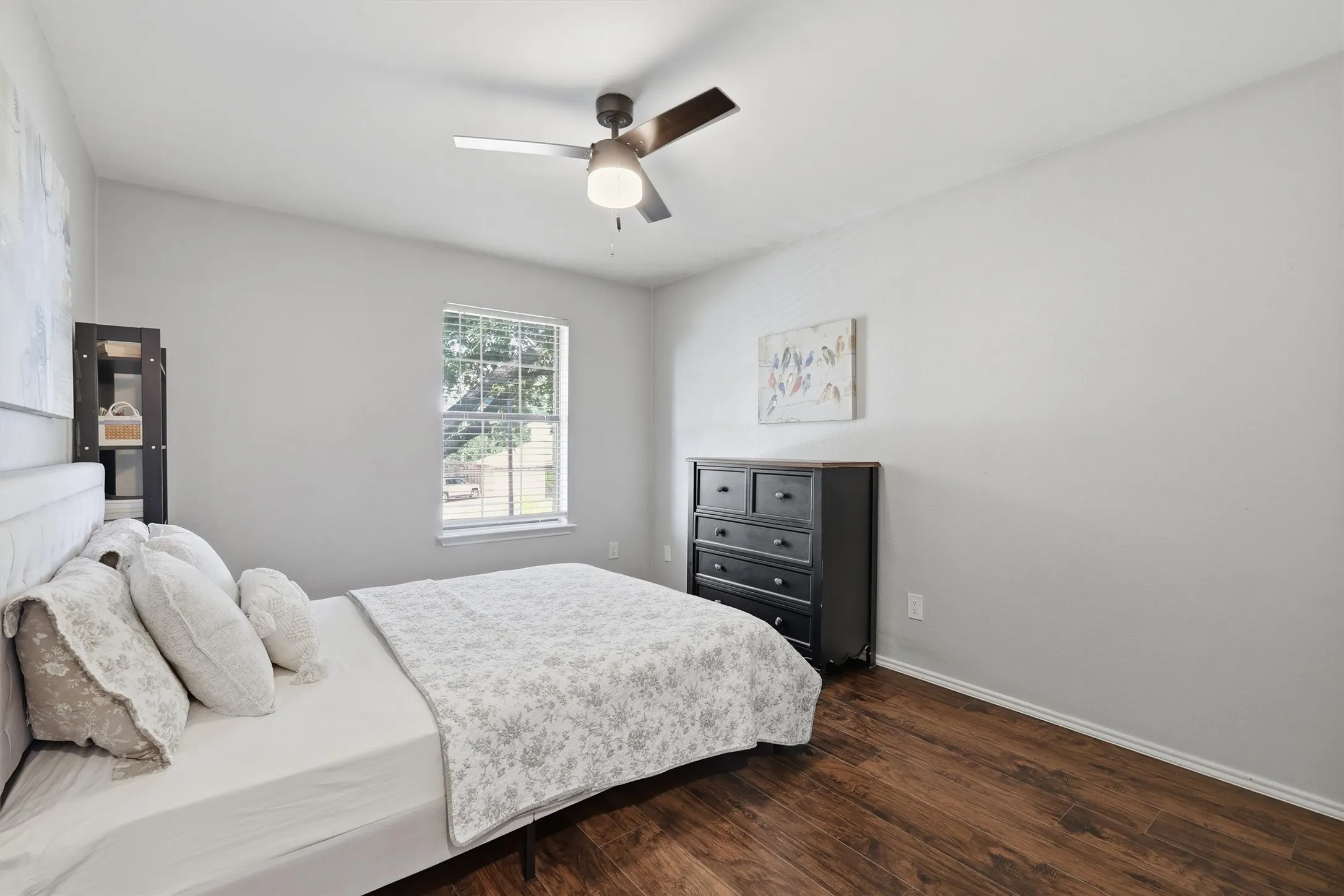 Interior room featuring wood-finish flooring, a window with blinds, and a ceiling fan with integrated lighting