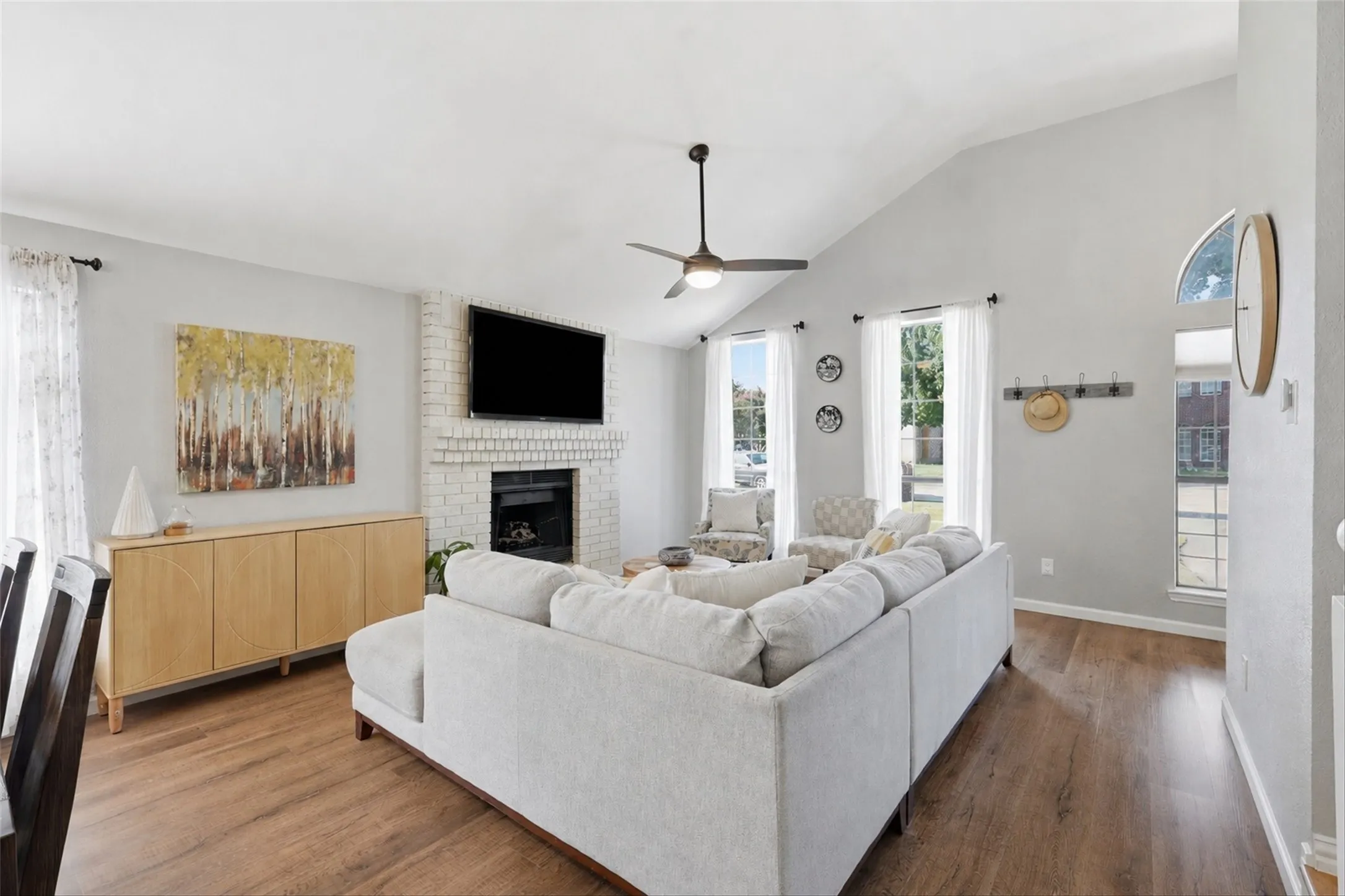 Spacious living area featuring vaulted ceilings, a ceiling fan, and wood-finish flooring