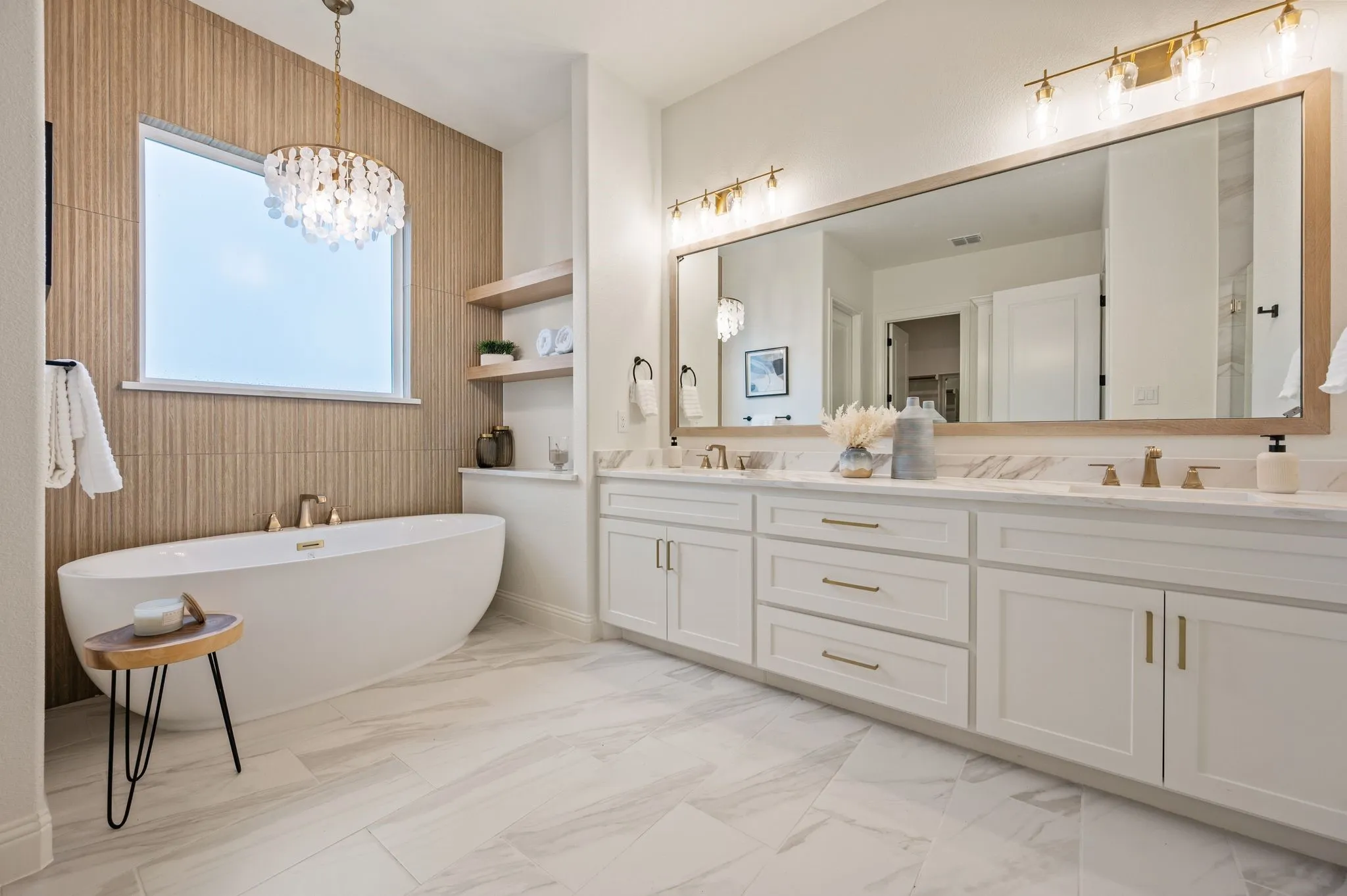 Freestanding soaking tub with a shell-motif chandelier, complemented by textured wall paneling and a large window