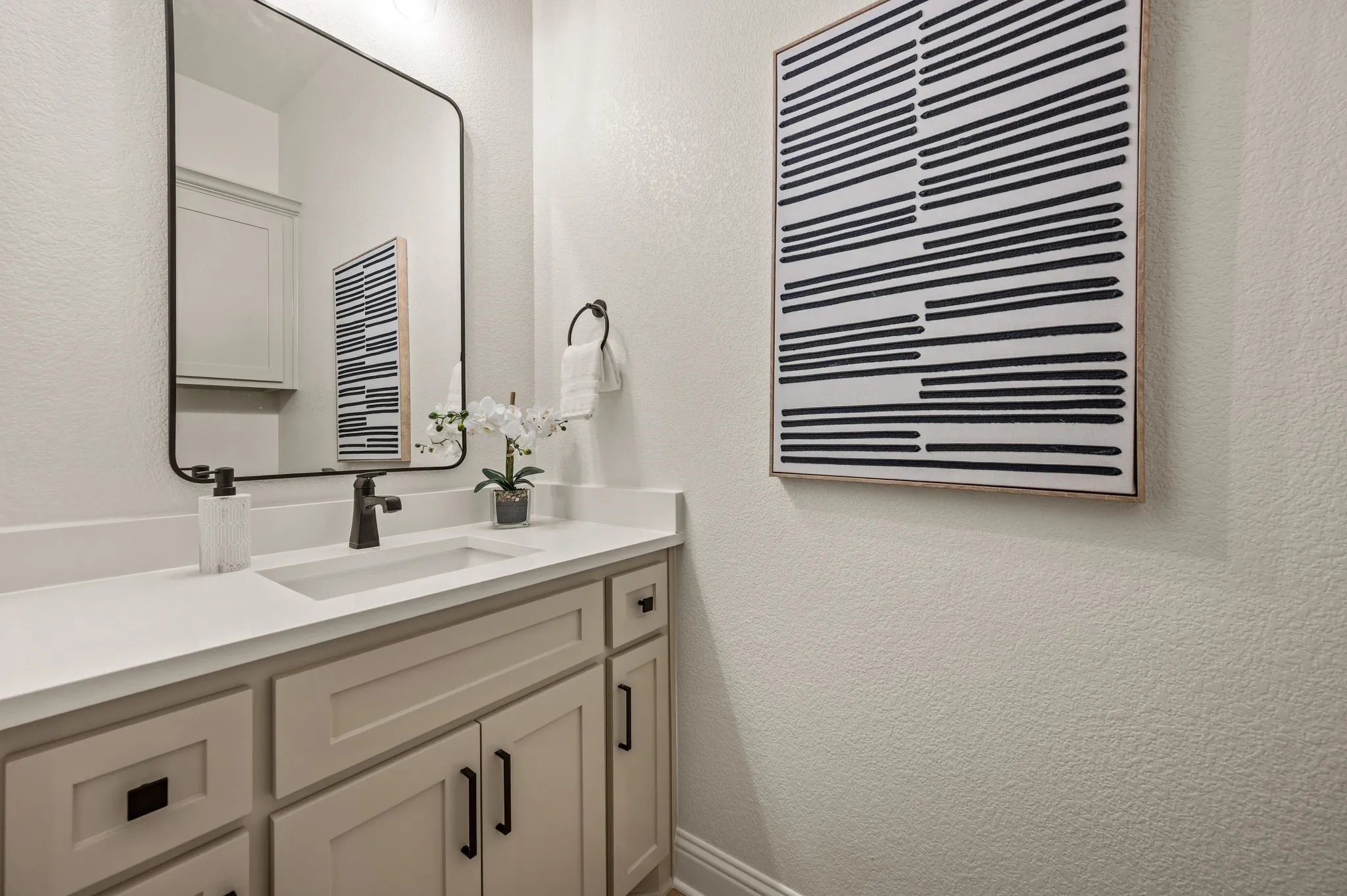 Bathroom vanity featuring a white countertop, undermount sink, and matte black faucet