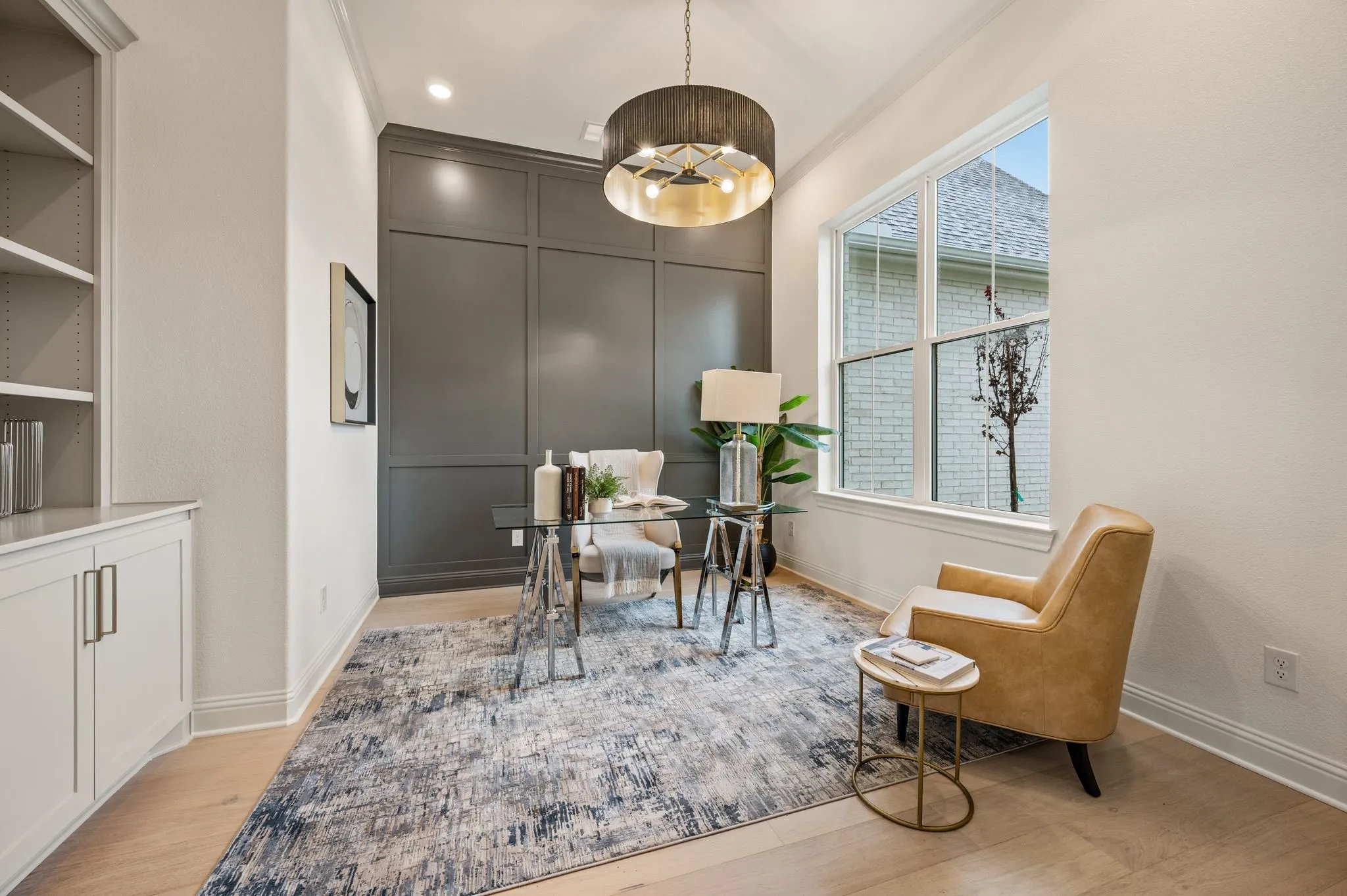 Room featuring a paneled accent wall, a built-in cabinet with open shelving, wood-finish flooring, and a large window