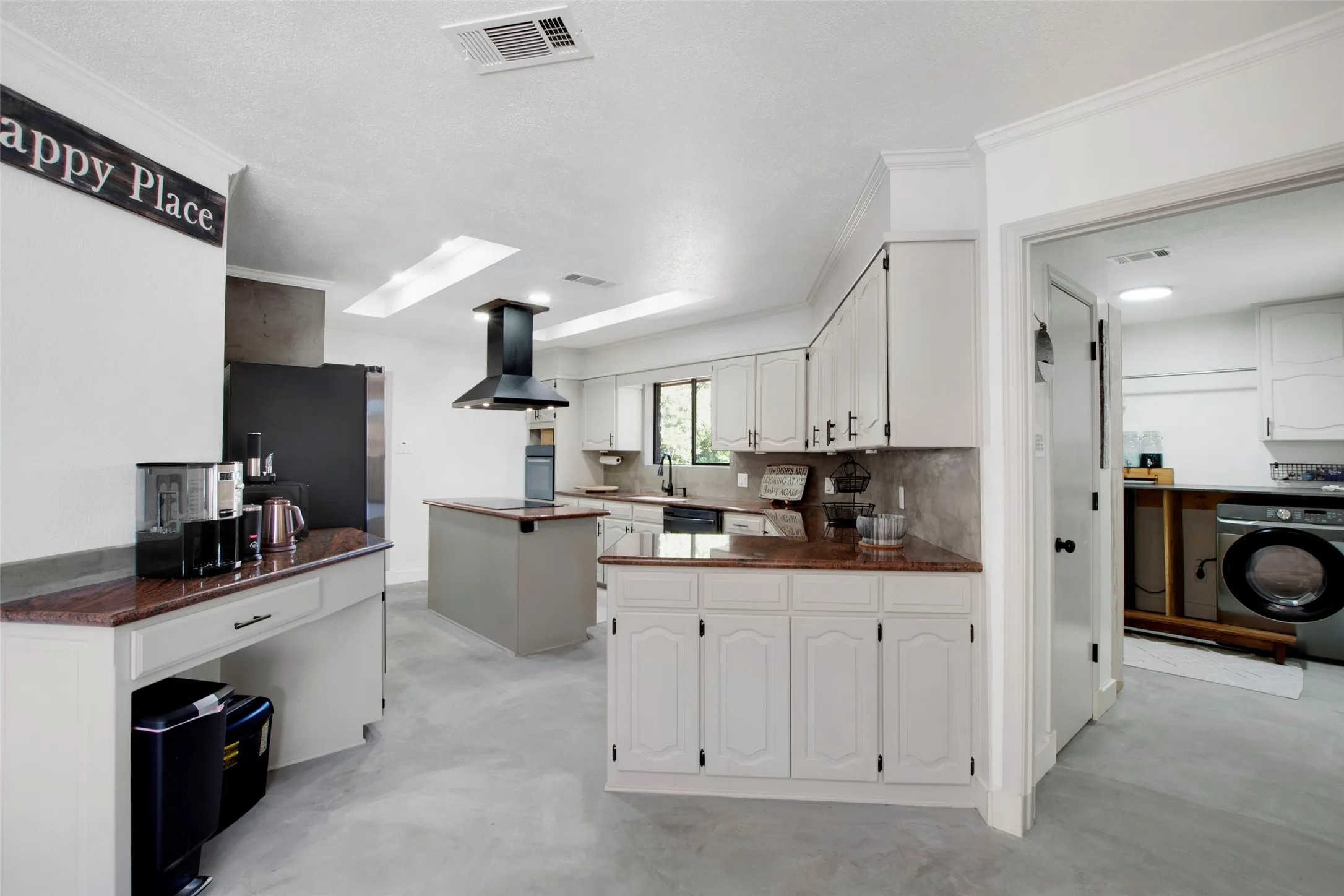 Kitchen featuring island range hood, a kitchen island, washer / dryer, and white cabinets