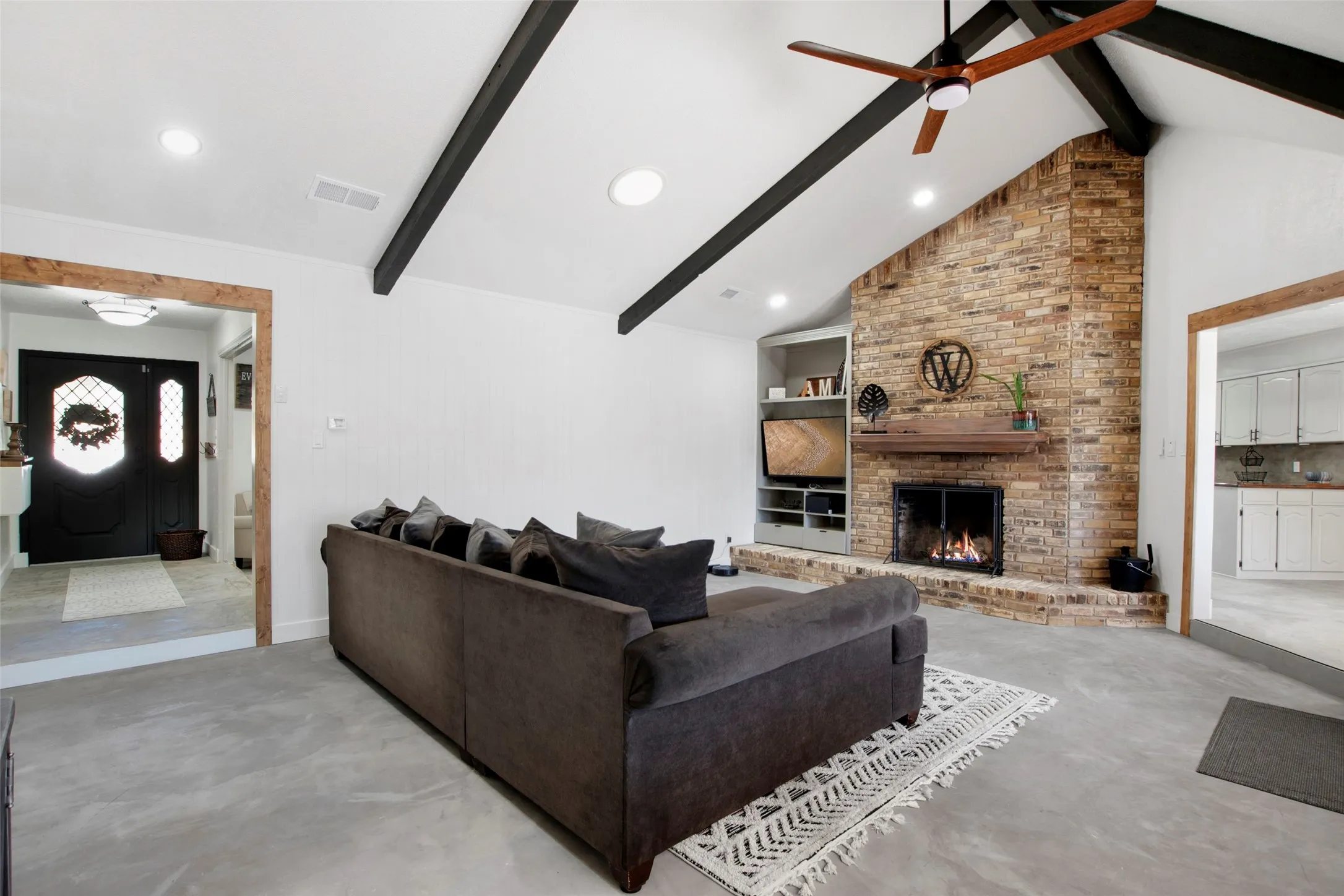 Living room featuring a fireplace, vaulted ceiling with beams, and ceiling fan