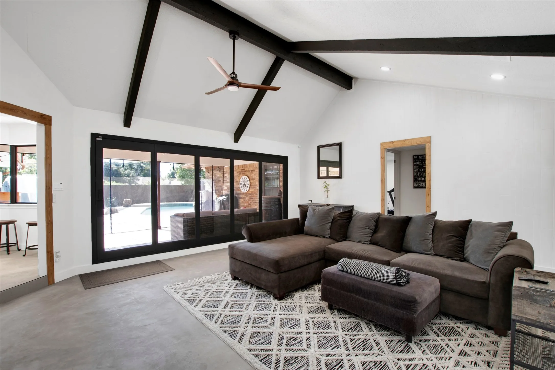 Living room featuring high vaulted ceiling, beamed ceiling, ceiling fan, and a healthy amount of sunlight