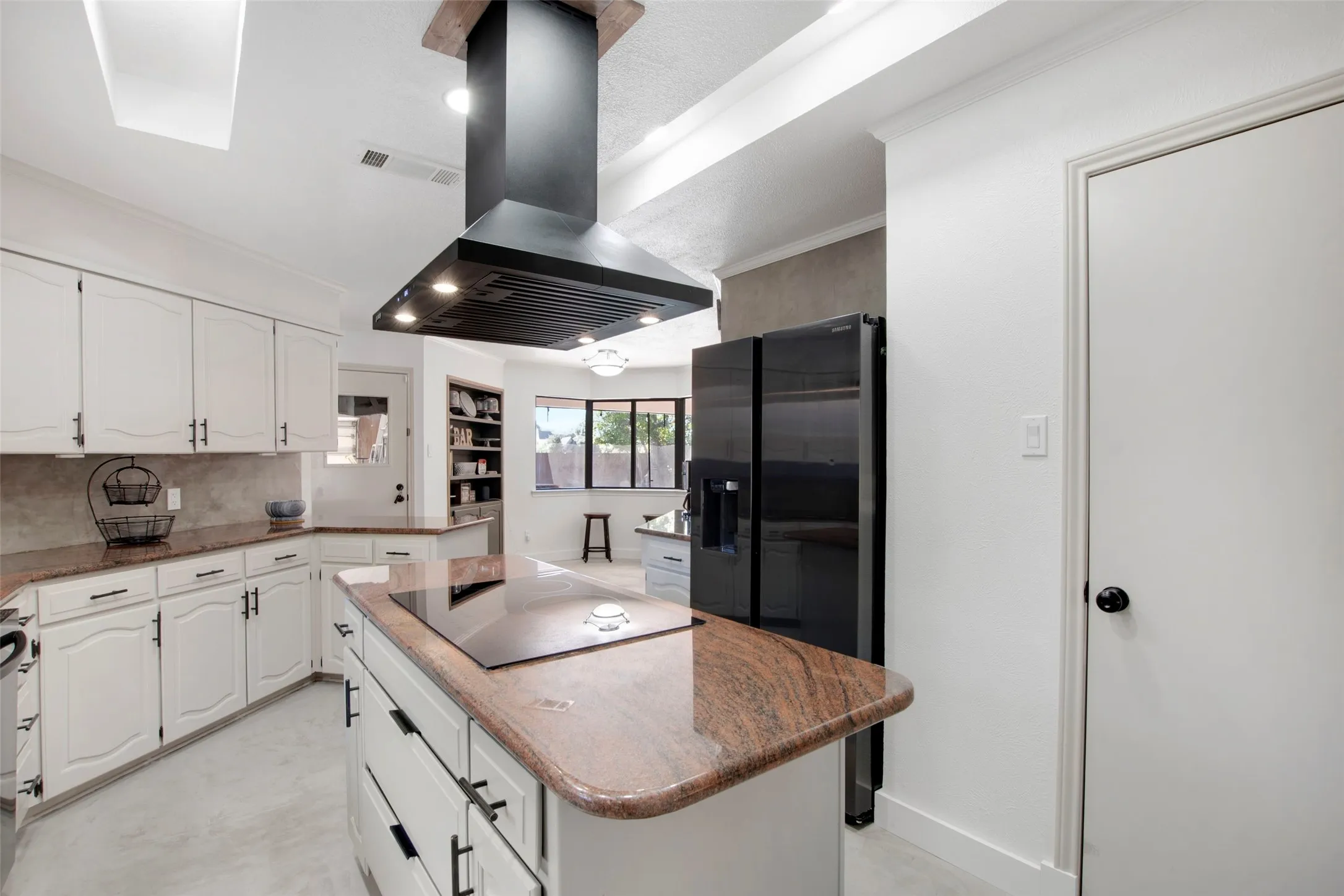Kitchen with island range hood, black appliances, white cabinetry, backsplash, and a center island