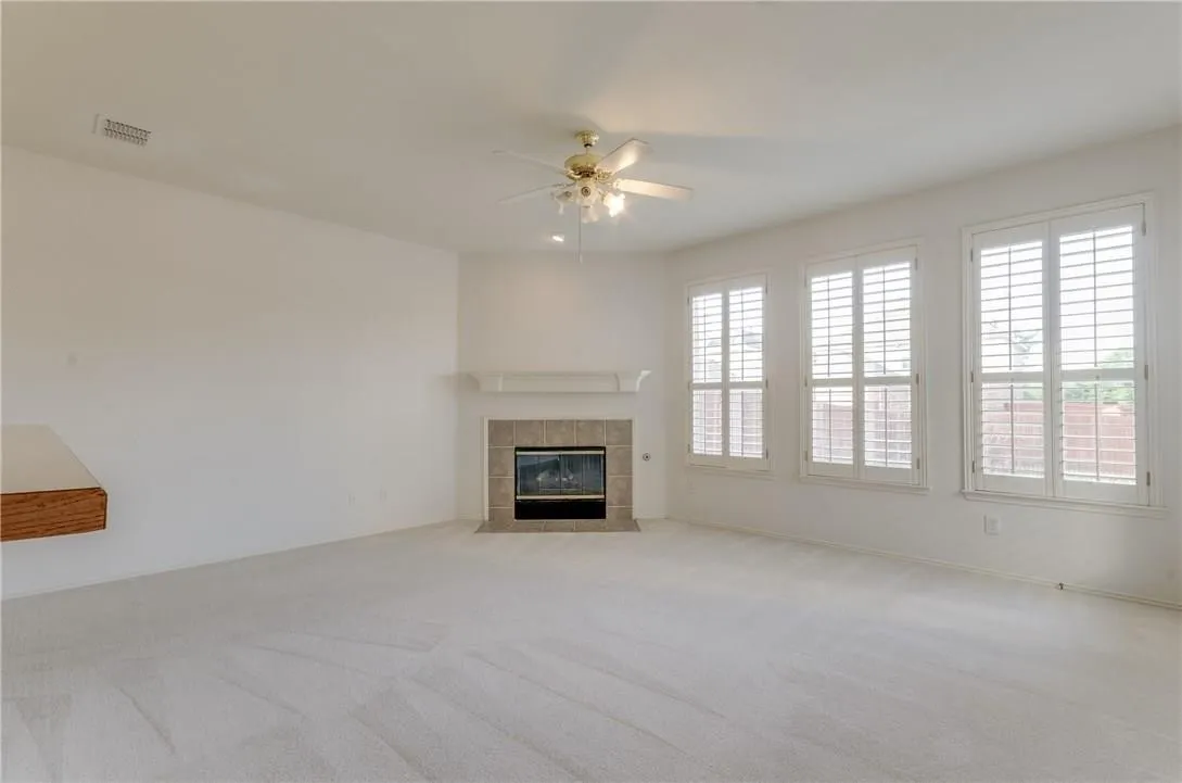 Spacious room featuring light-toned carpeting and a ceiling fan