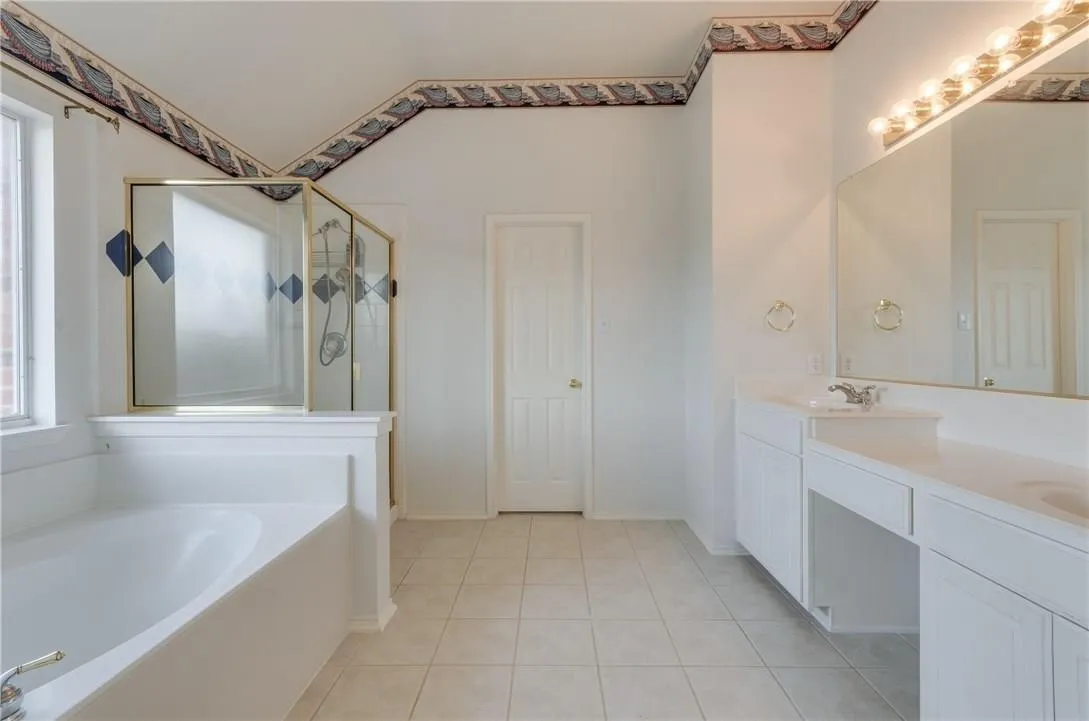 Spacious bathroom featuring a built-in tub, separate shower with framed glass enclosure, and dual vanity with integrated countertop