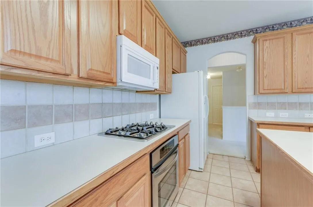 Kitchen featuring light wood cabinetry, a built-in gas cooktop, and a wall-mounted microwave