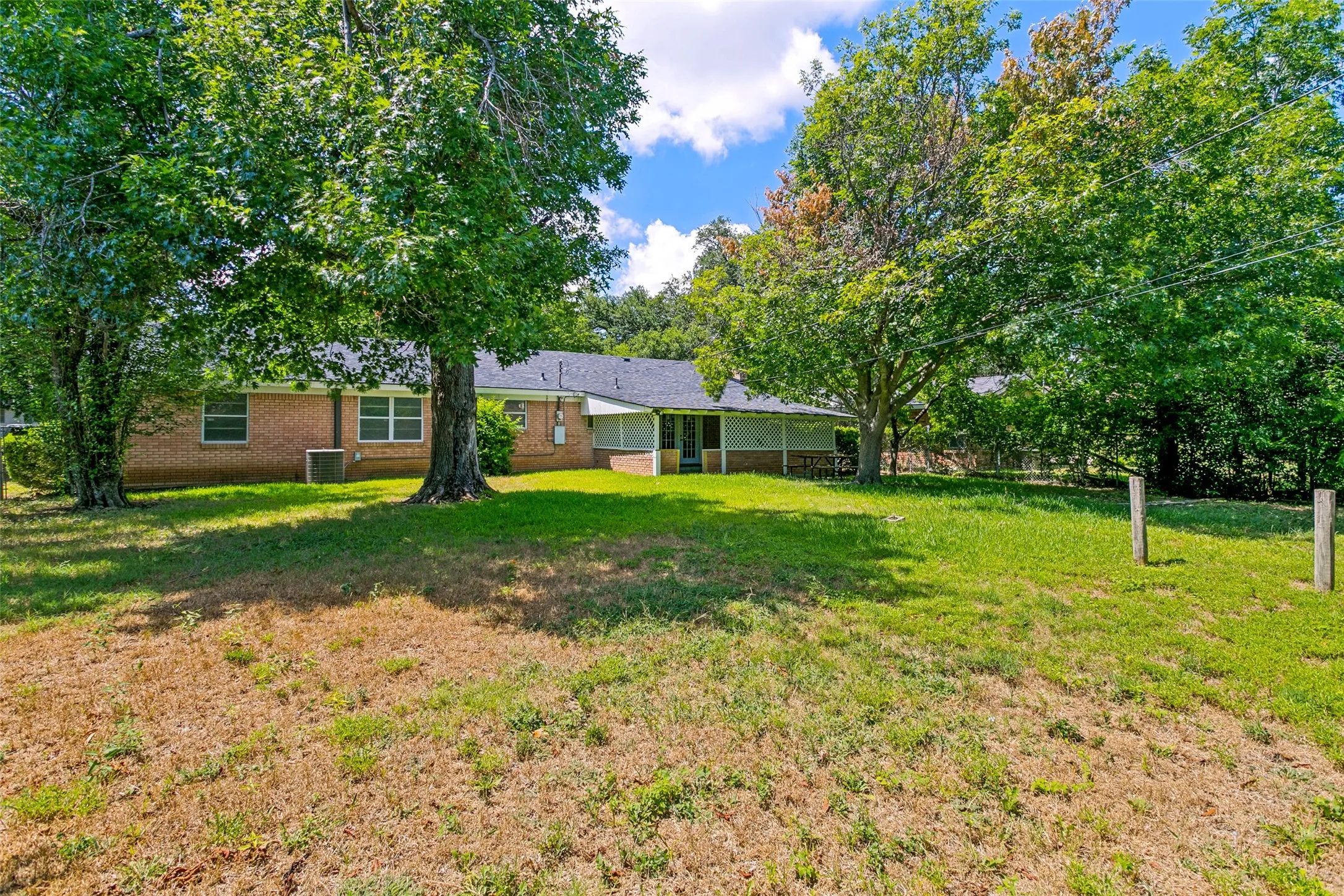 Expansive rear yard featuring mature trees and a brick exterior home with multiple windows