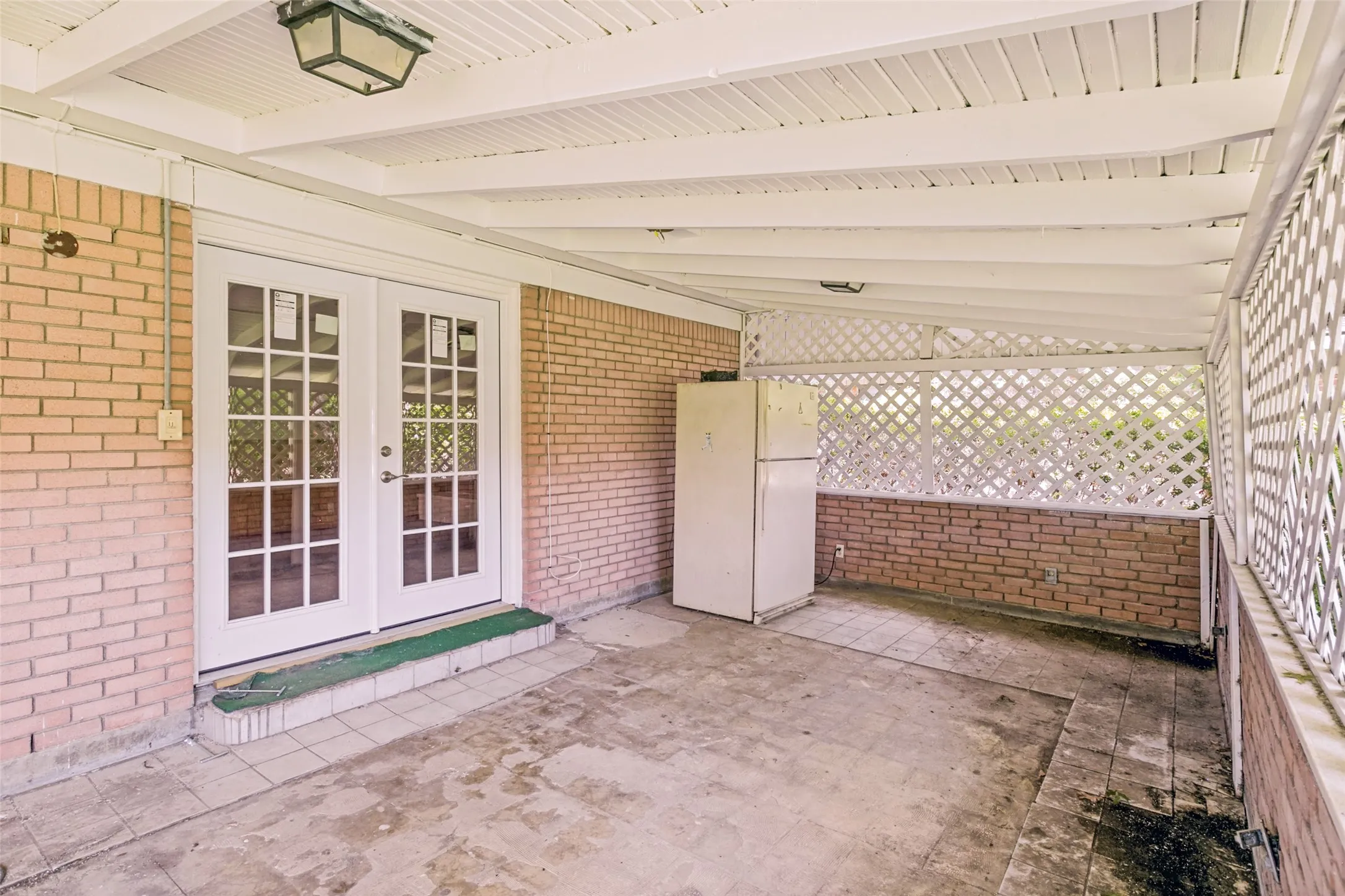 Covered patio featuring brick walls and a white lattice privacy screen