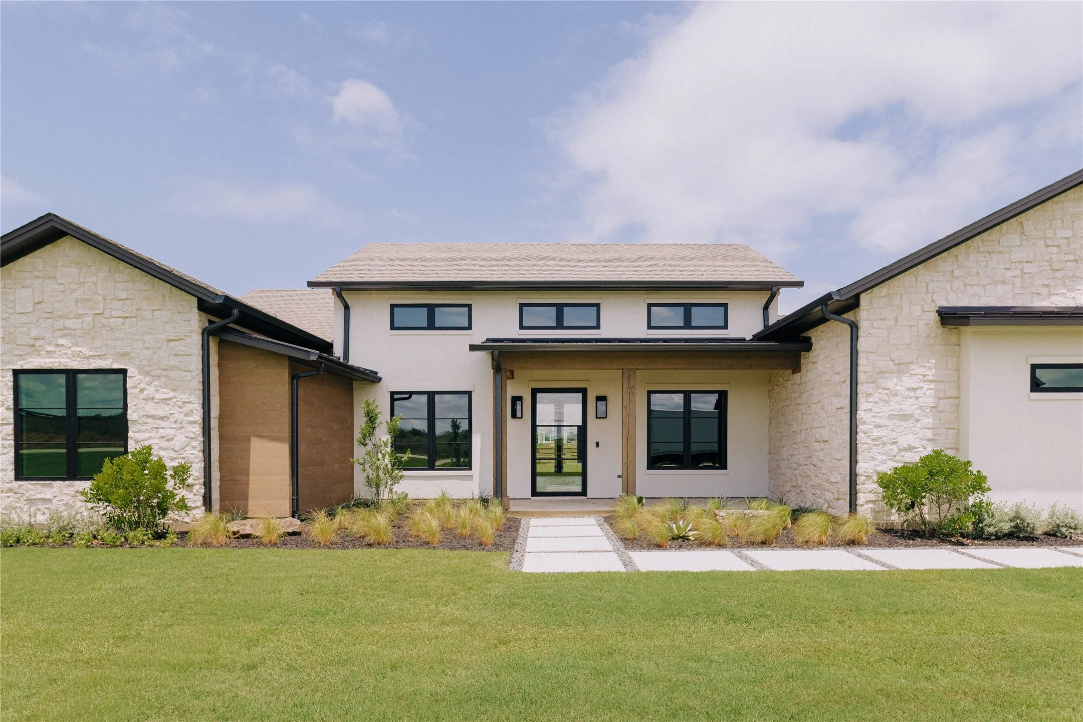 Modern farmhouse residence featuring a striking cream brick exterior with black-trimmed windows and a welcoming covered entry