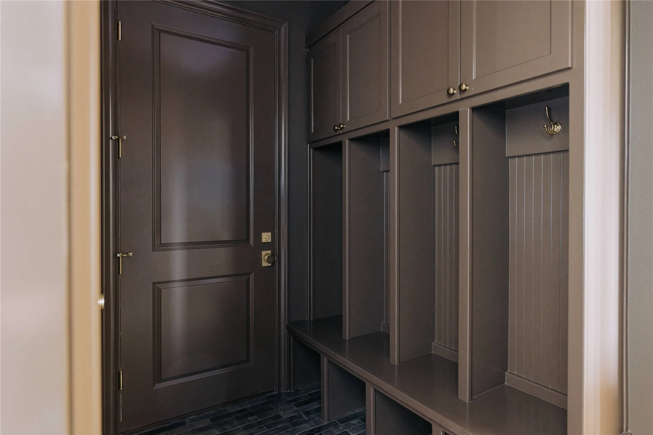 Built-in mudroom organization system with upper cabinetry, open cubbies with hooks, and bench seating