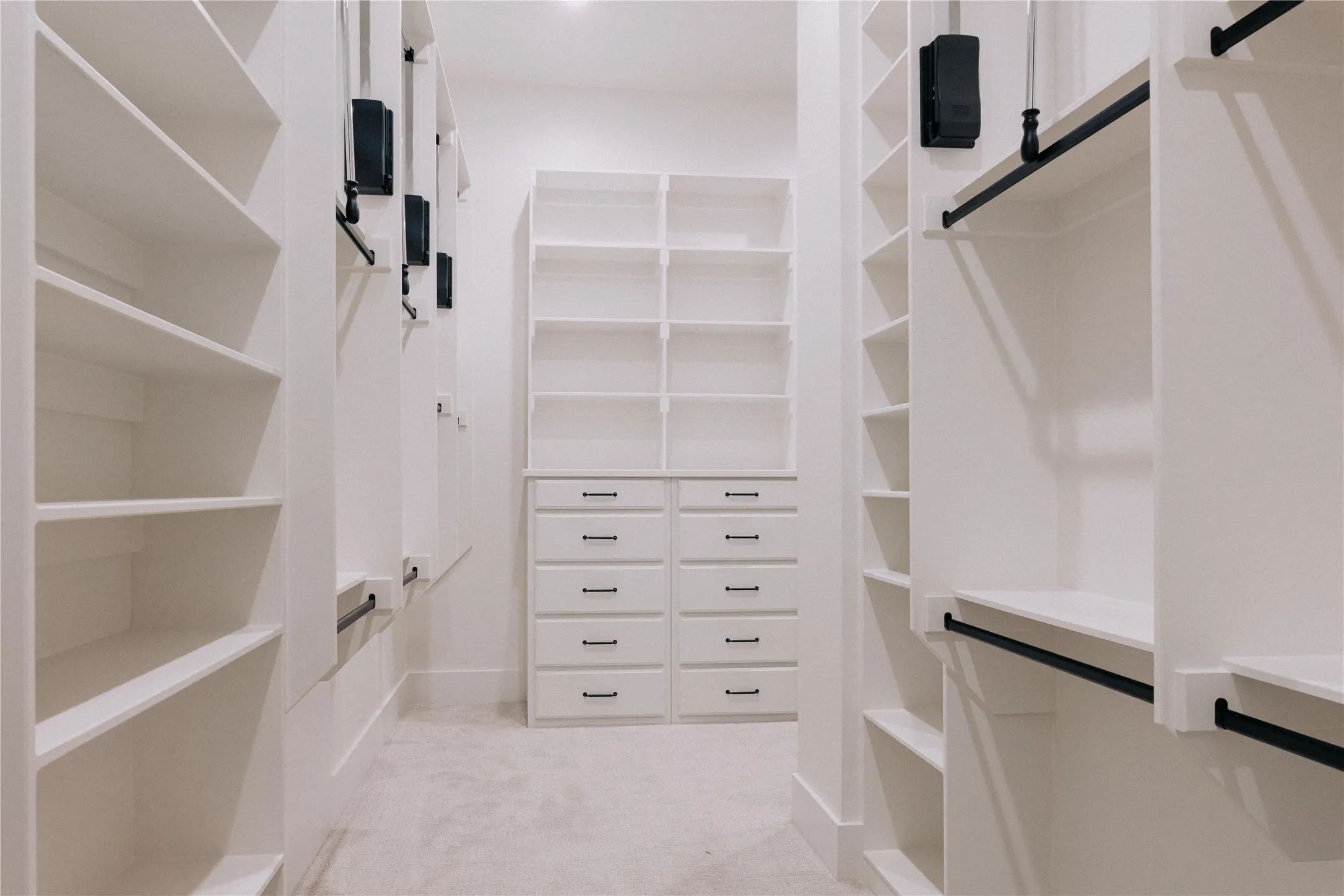 Luxurious walk-in closet featuring extensive built-in cabinetry with multiple drawers and open shelving throughout
