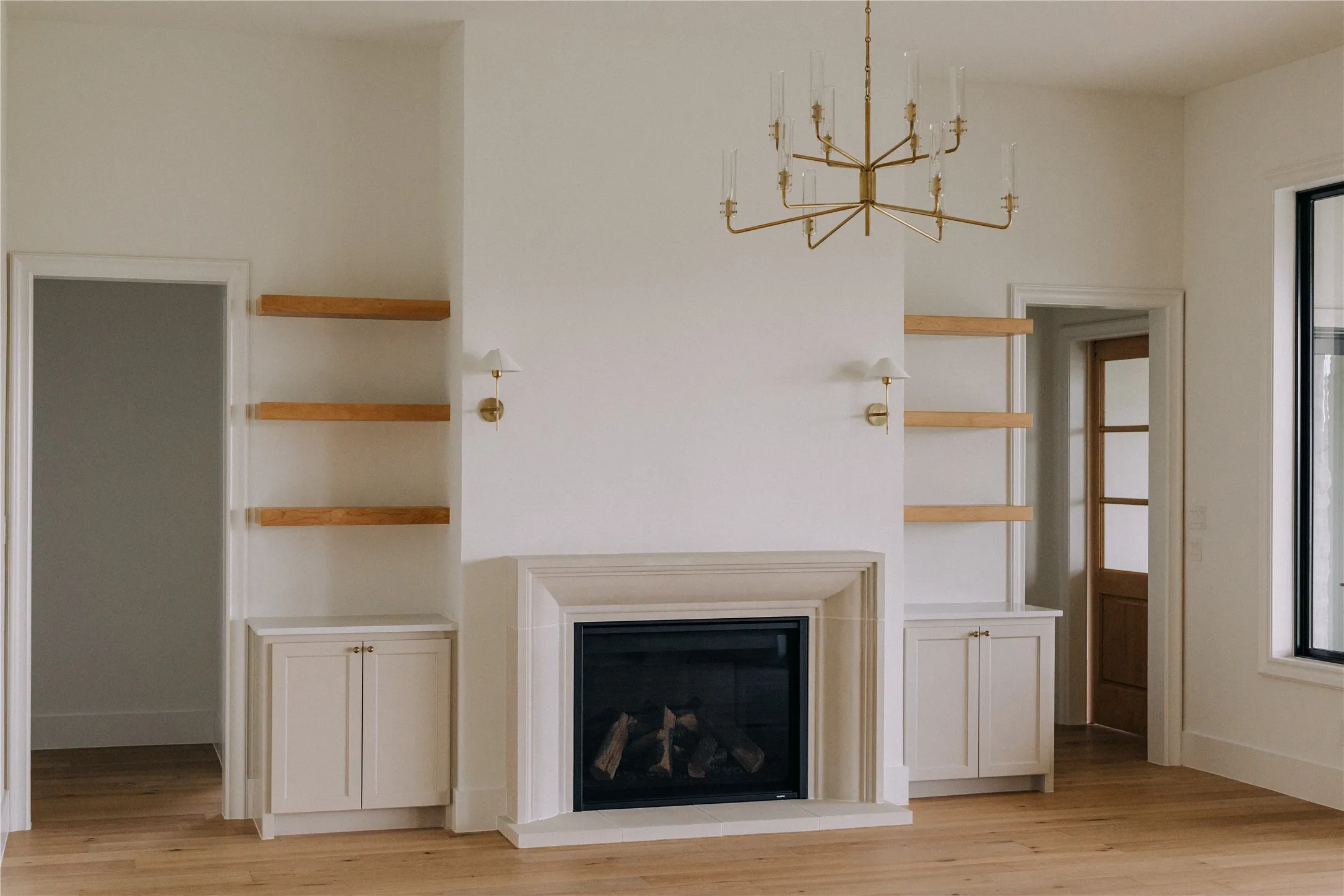 Living area featuring a stone fireplace with a black insert, flanked by built-in cabinetry and natural wood shelving
