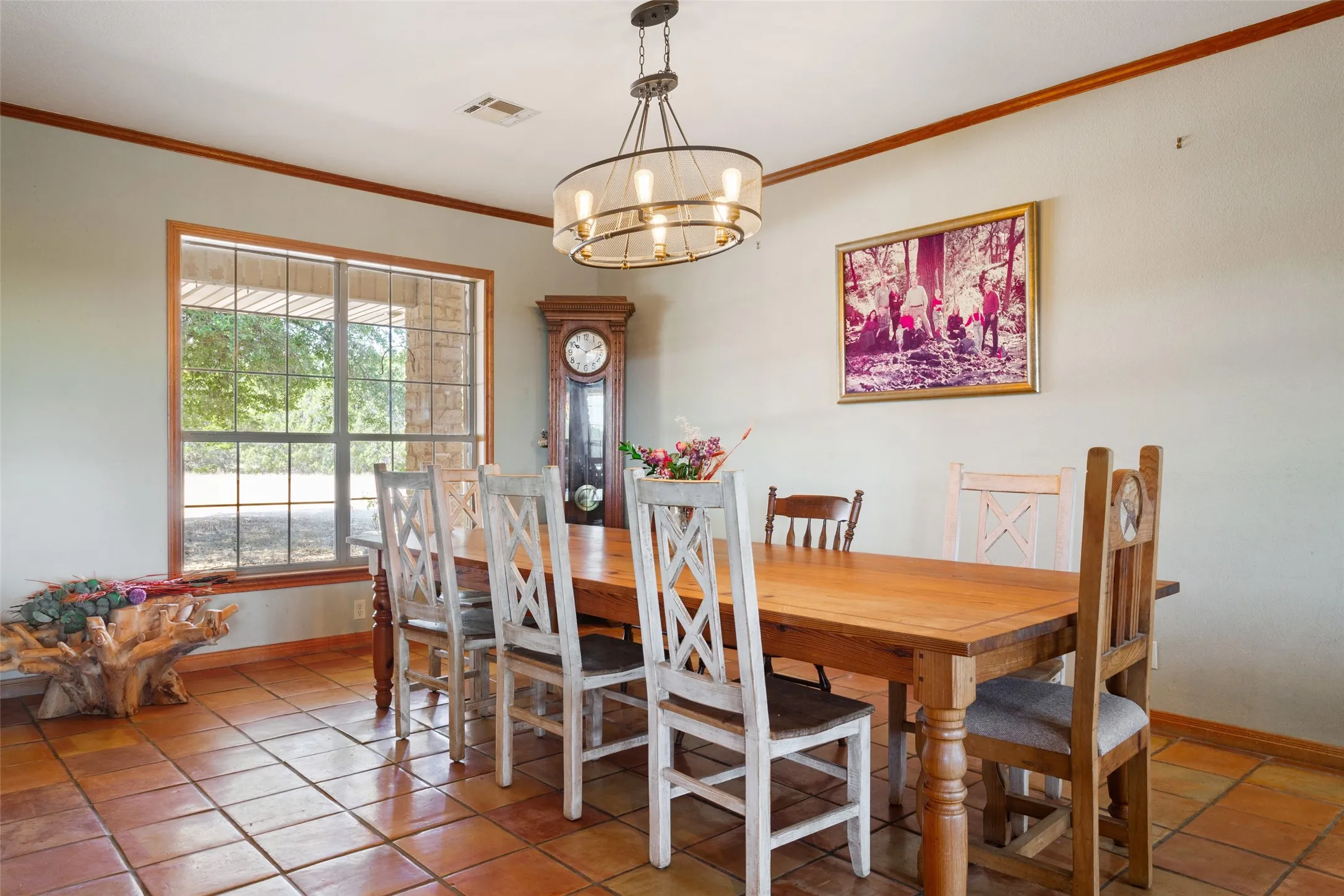 Spacious room featuring terracotta tile flooring, a large multi-pane window, and a contemporary chandelier