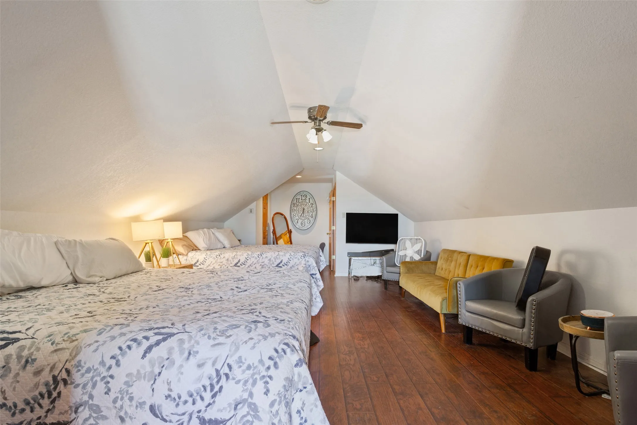 Spacious loft area featuring sloped ceilings, recessed lighting, wood-finish flooring, and a ceiling fan
