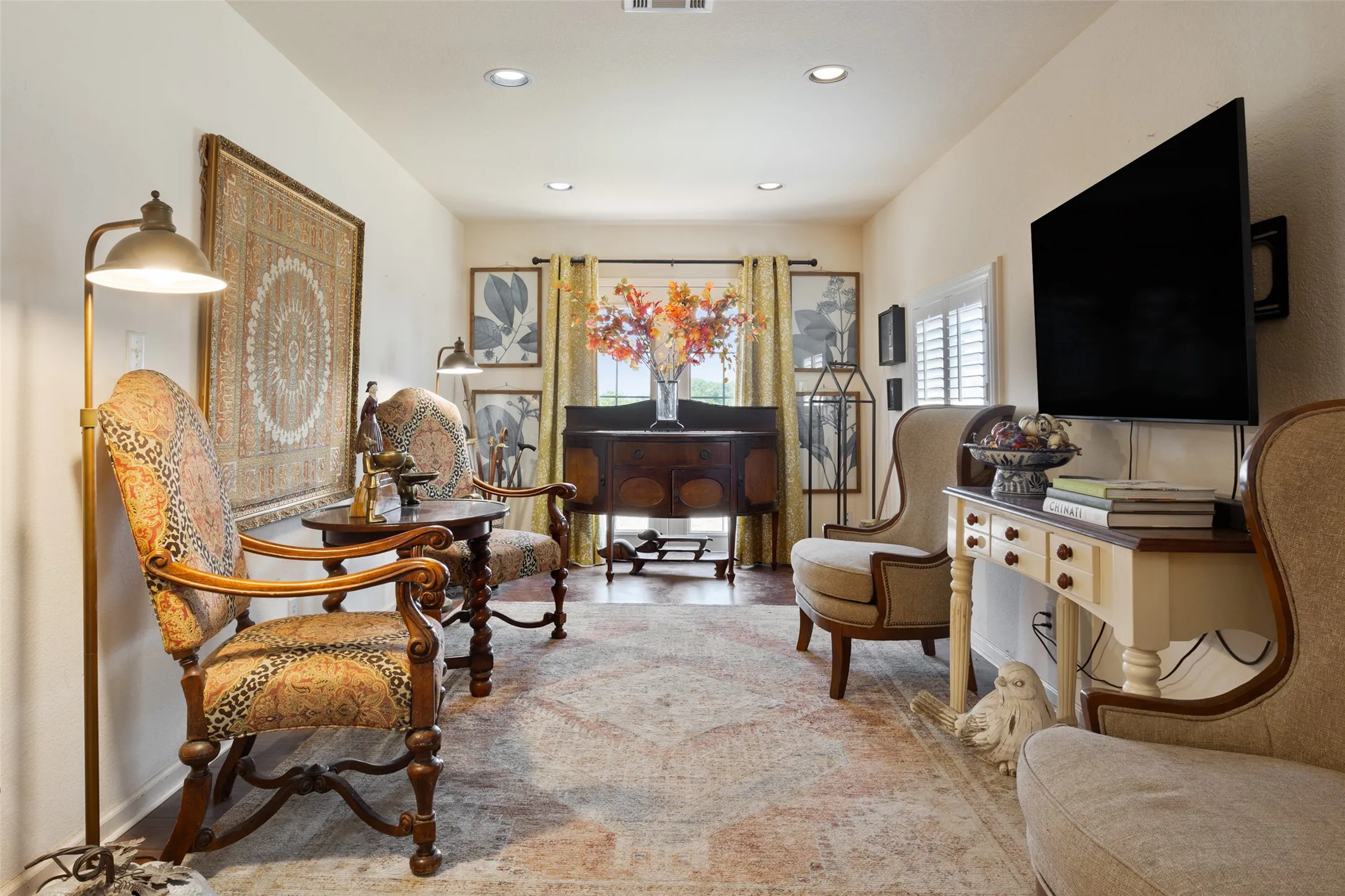 Recessed ceiling lighting illuminates this living space featuring wood-finish flooring and a decorative area rug