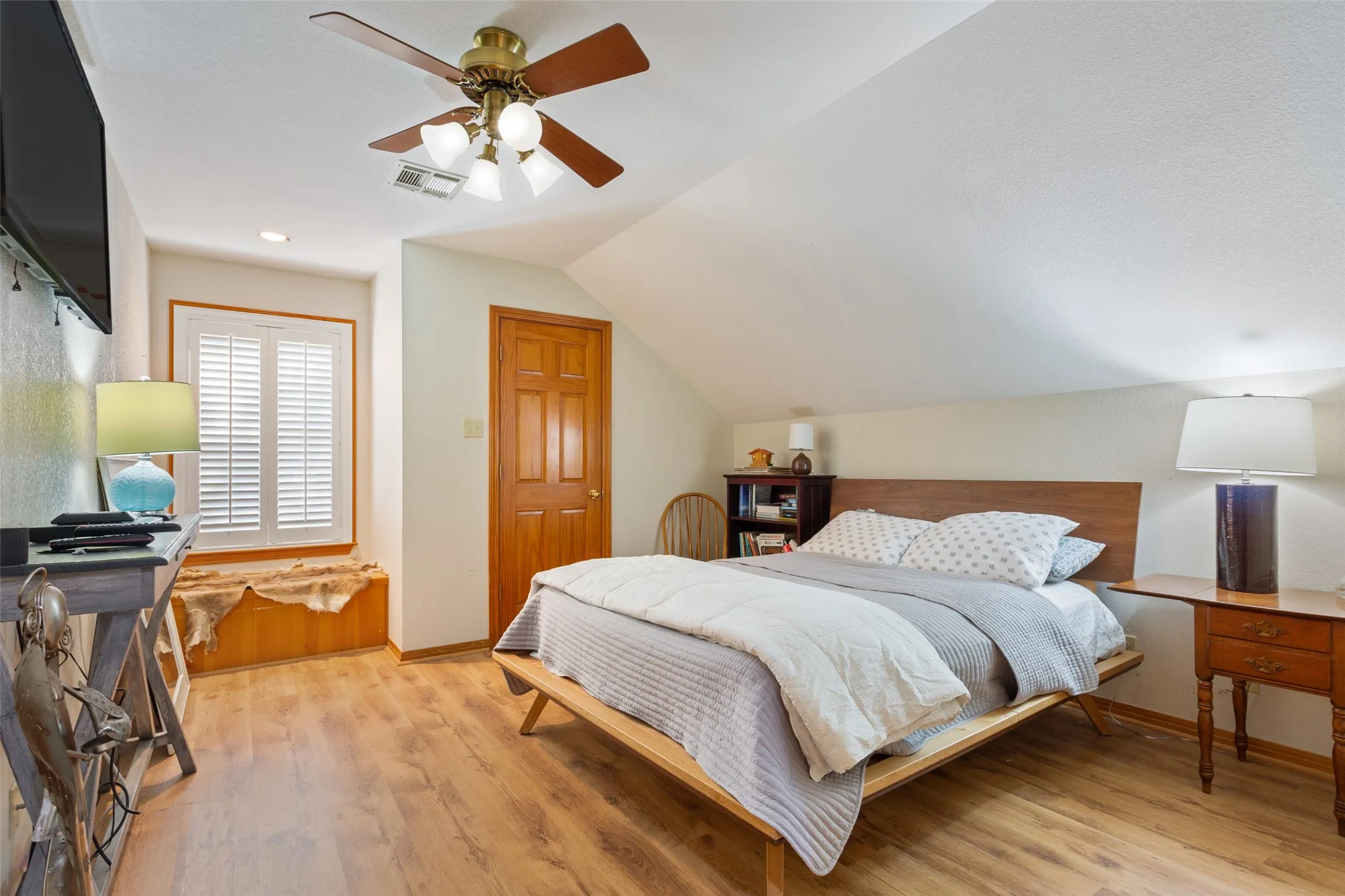 Wood-finish flooring throughout, complemented by a sloped ceiling and recessed lighting