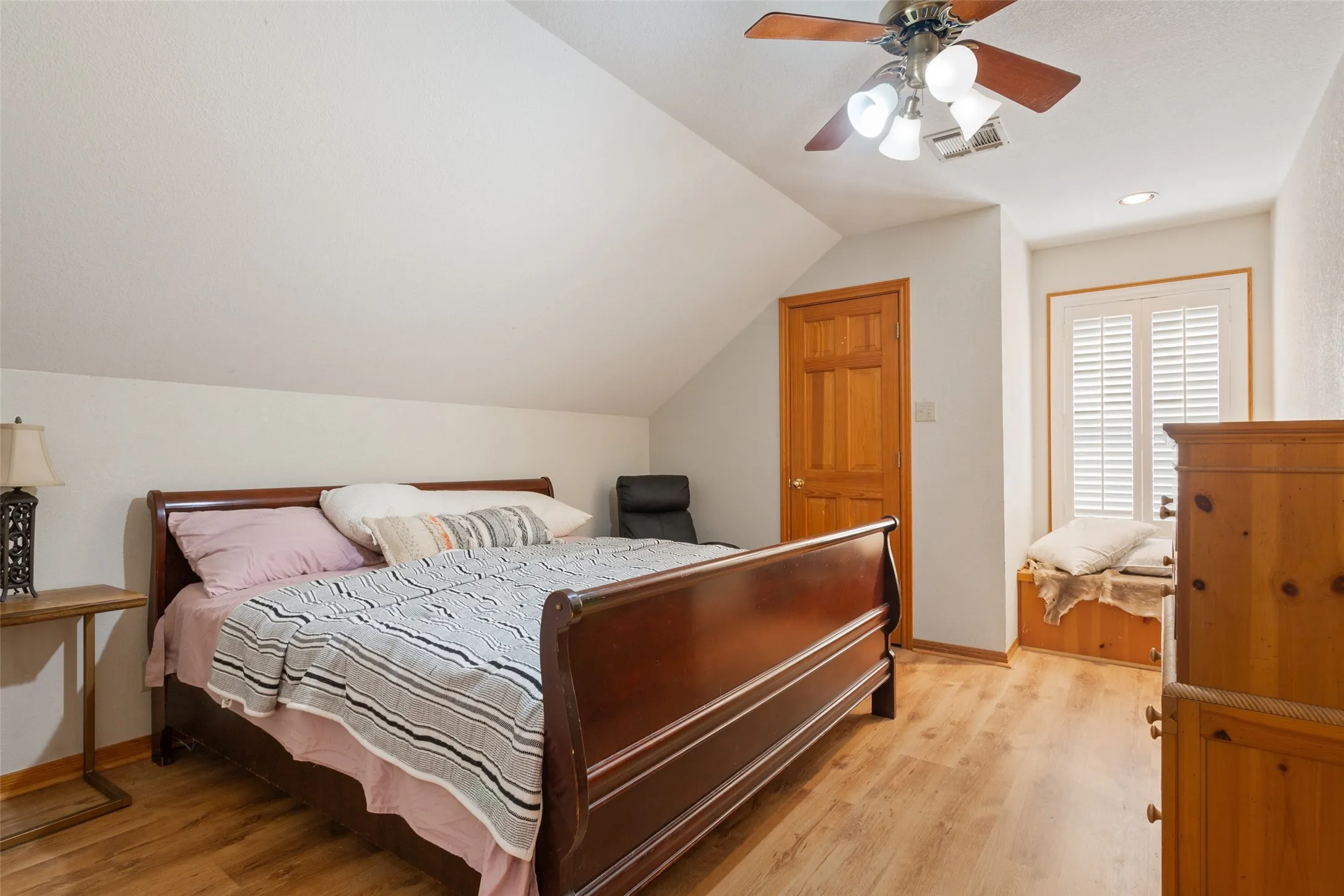 Room featuring wood-finish flooring, a sloped ceiling, and a ceiling fan with integrated lighting