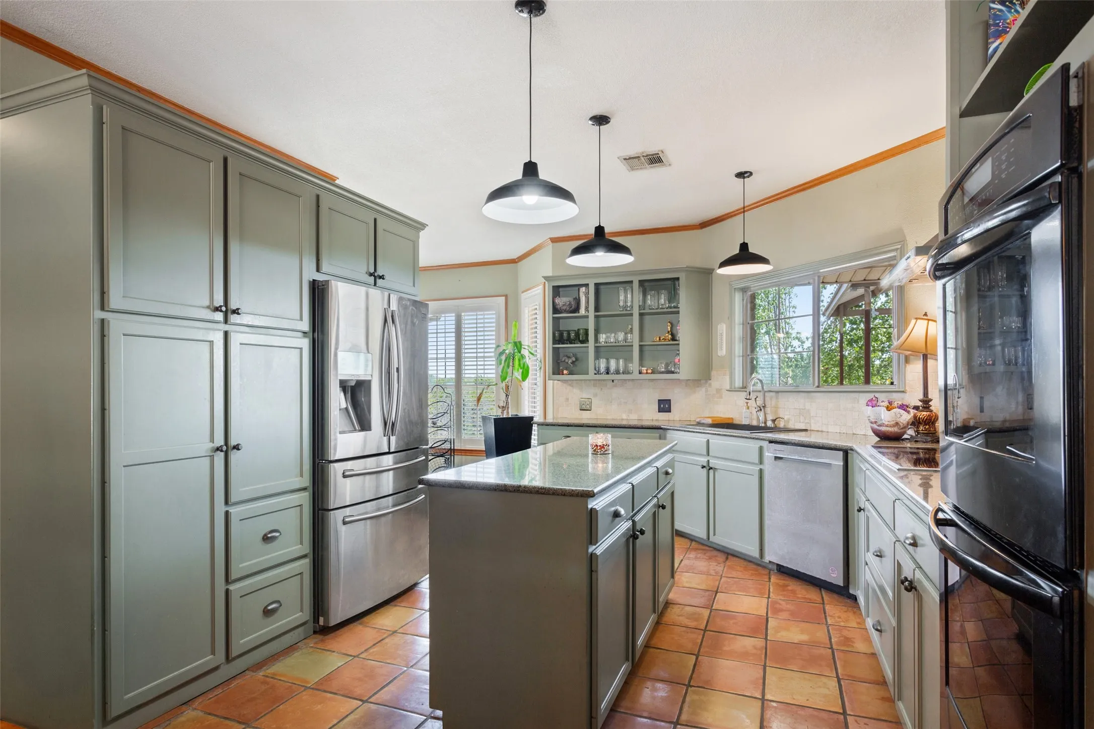 Kitchen featuring a central island with granite countertop, terracotta tile flooring, stainless steel appliances, abundant cabinetry, and a double wall oven