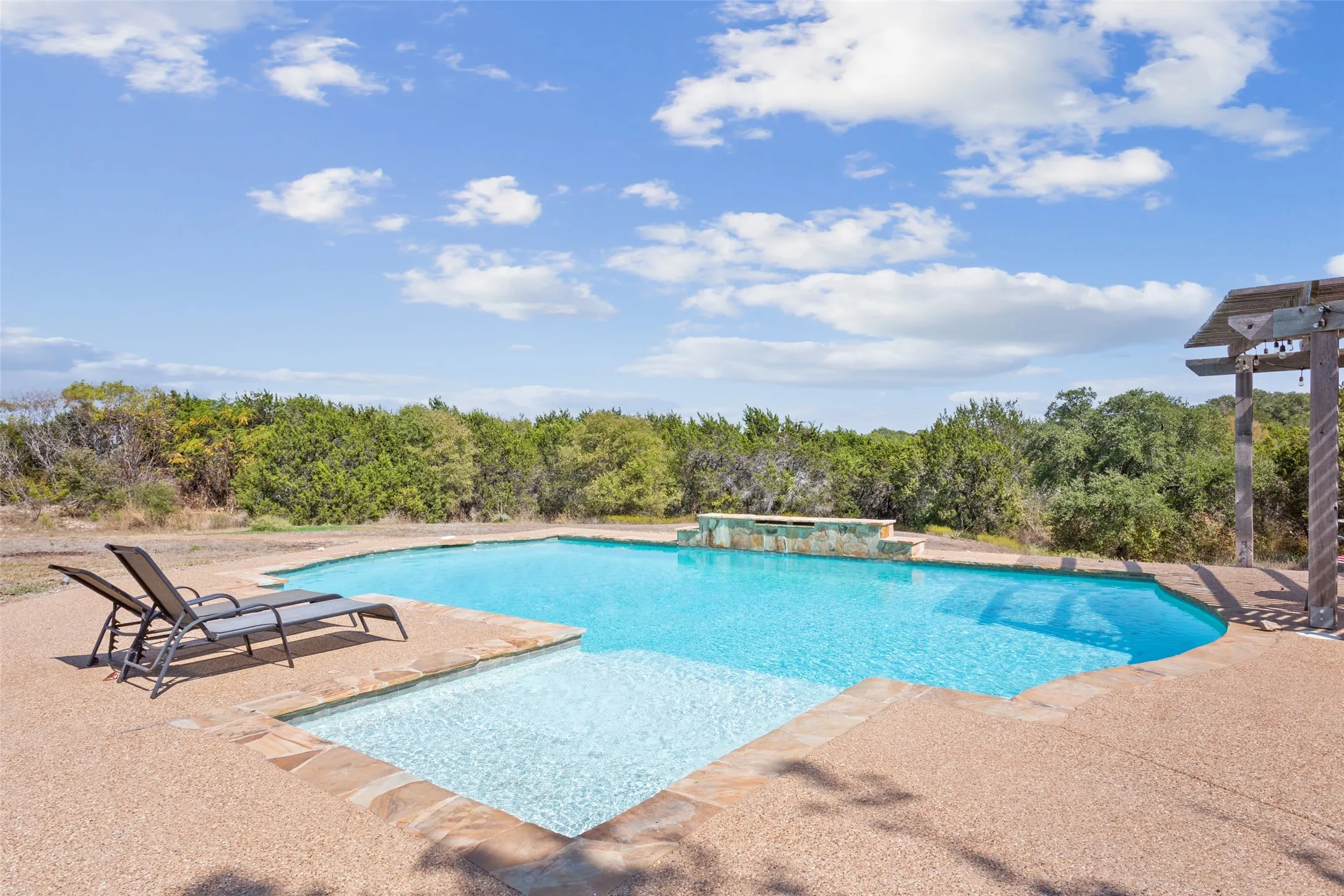 Freeform swimming pool featuring a tanning ledge and integrated waterfall