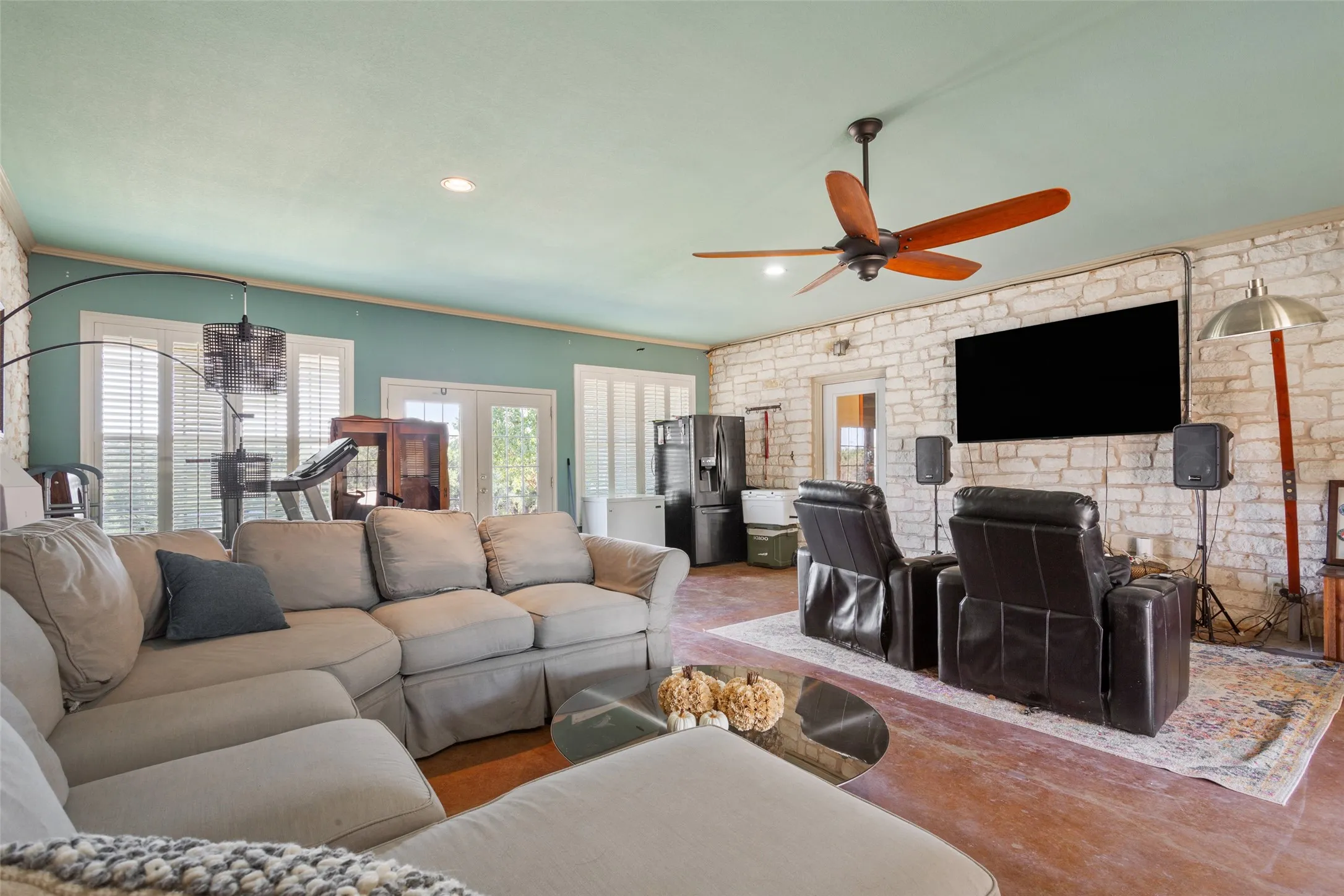 Spacious room featuring exposed stone walls, recessed lighting, and a prominent ceiling fan