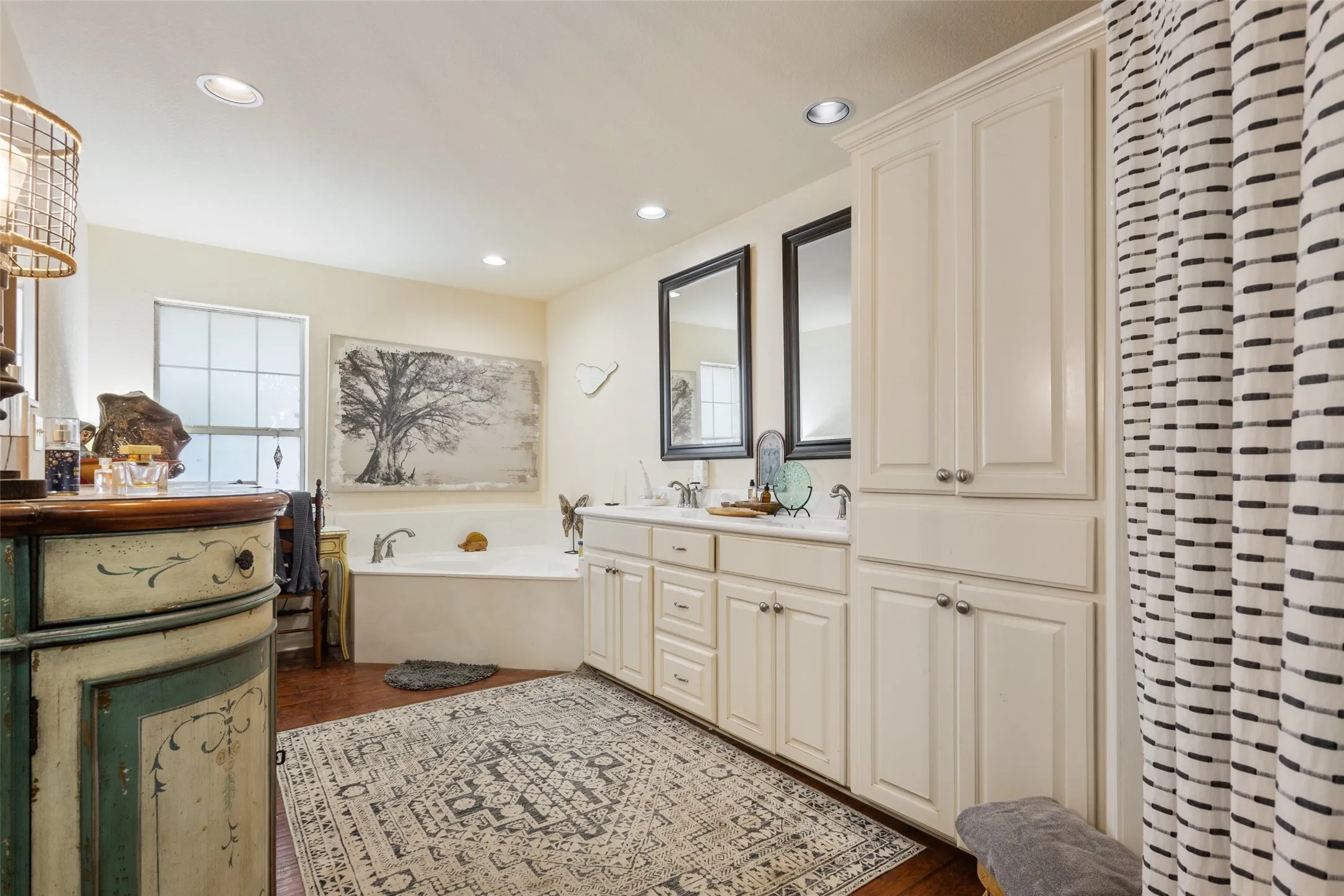 Bathroom featuring a built-in tub, dual sink vanity with white cabinetry, and recessed lighting
