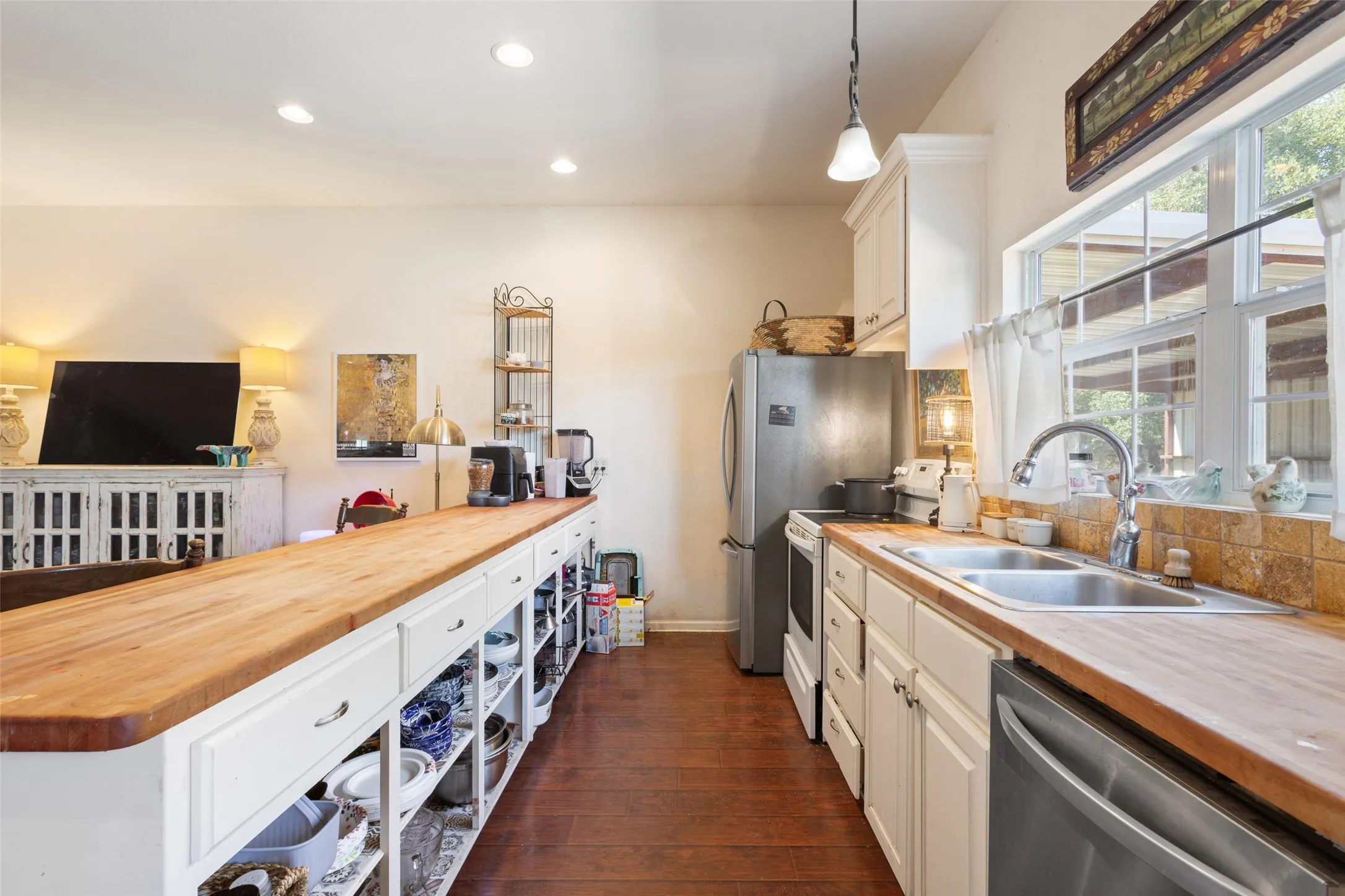 Kitchen featuring wood-finish countertops, white cabinetry, a double basin stainless steel sink, and a tiled backsplash