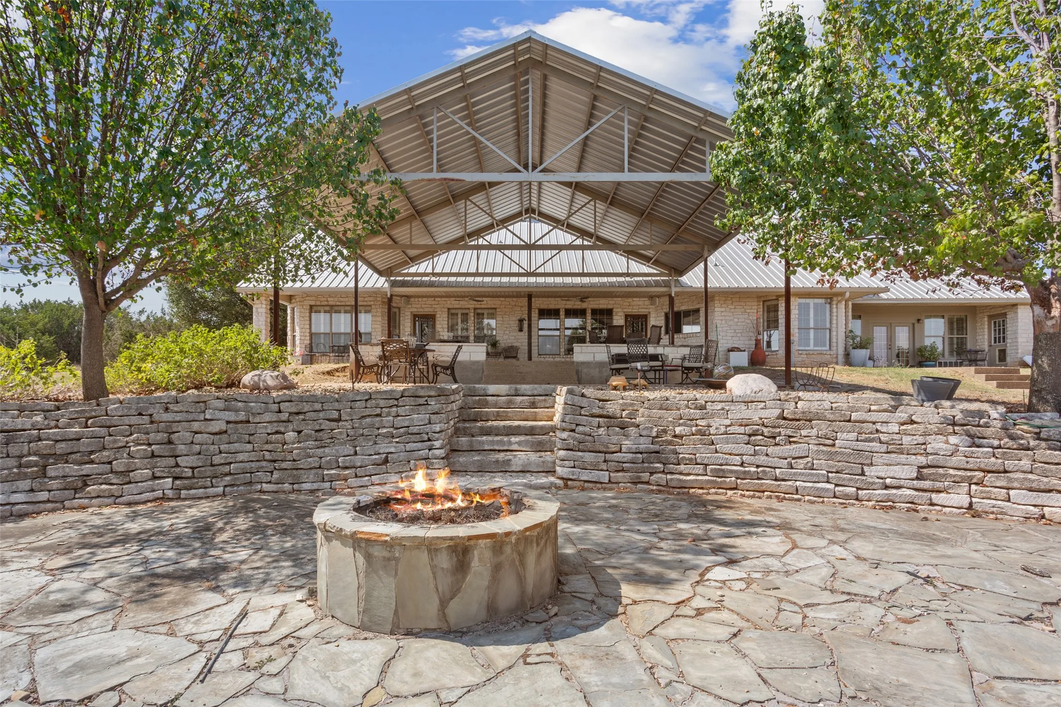 Expansive outdoor living area featuring a stone fire pit, flagstone patio, and a stone retaining wall