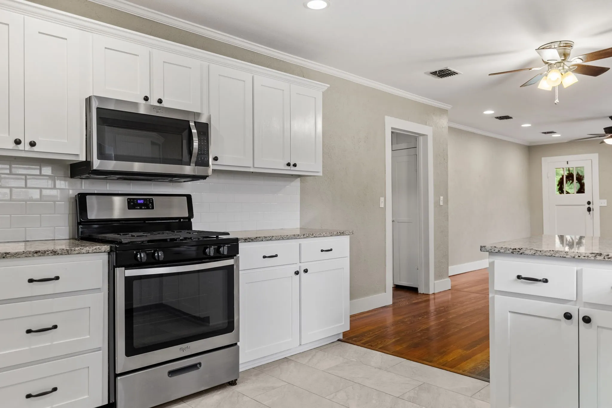 Modern kitchen featuring white shaker cabinetry, stainless steel appliances, granite countertops, and subway tile backsplash