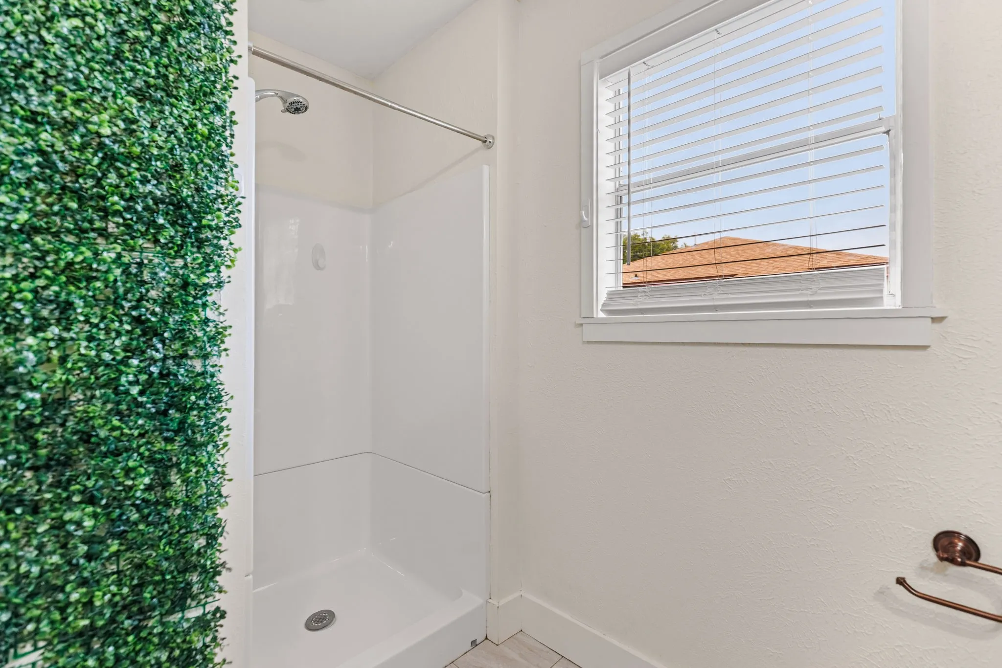 Shower stall with bright white surround and integrated shelving, featuring a chrome shower head and rod