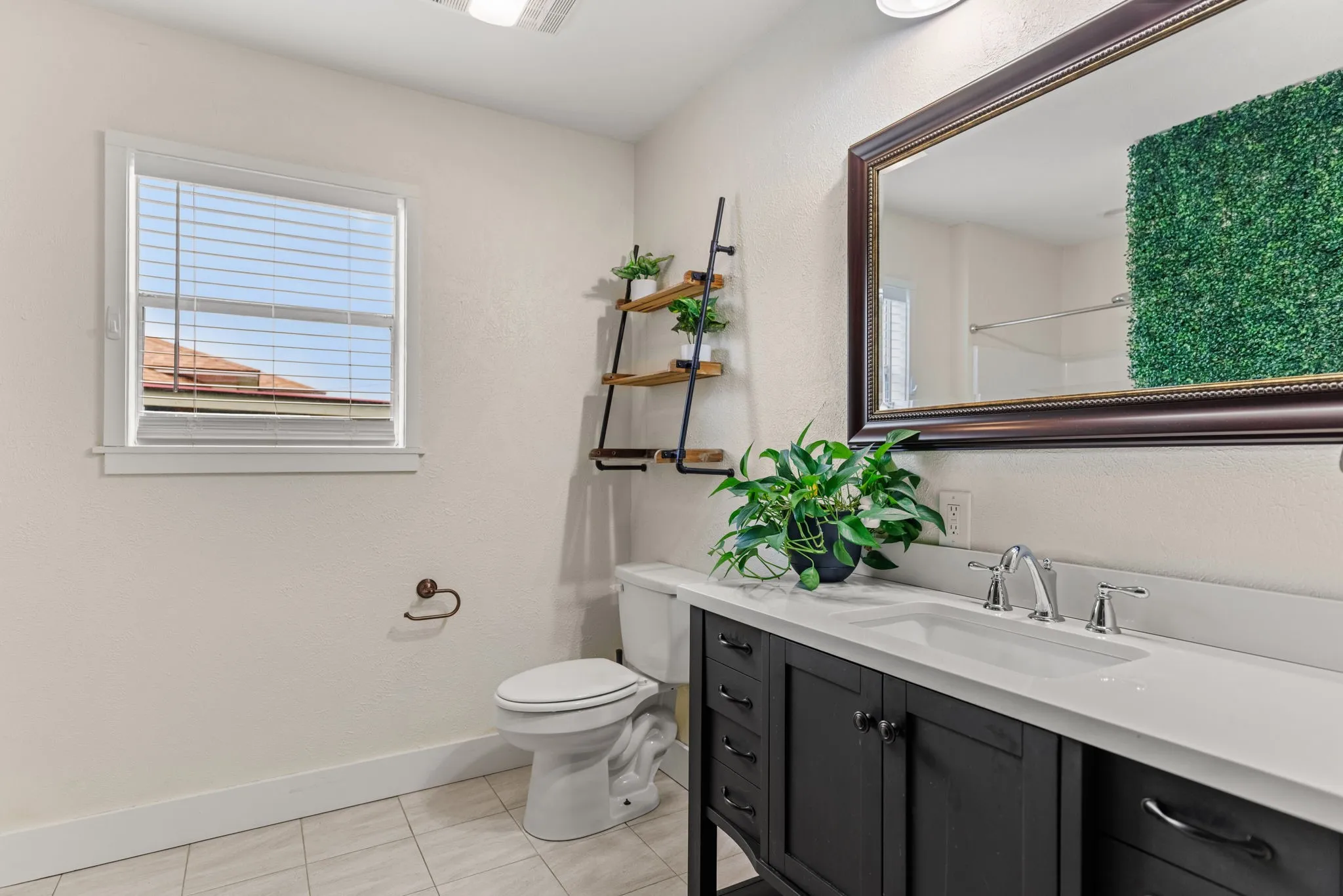 Bathroom featuring a dark wood vanity with a white countertop and undermount sink, a framed mirror, and tile flooring