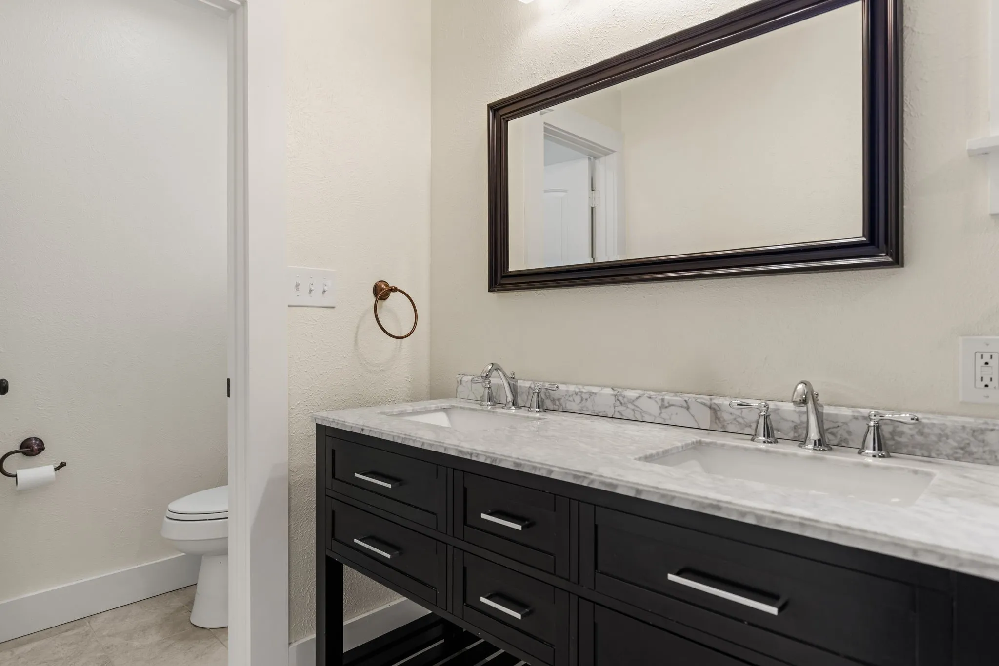 Double vanity with dark wood cabinetry, dual undermount sinks, and a light-toned countertop