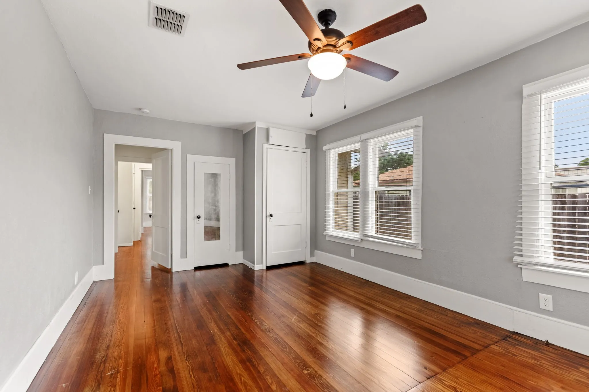 Hardwood flooring extending throughout, complemented by a ceiling fan with integrated lighting
