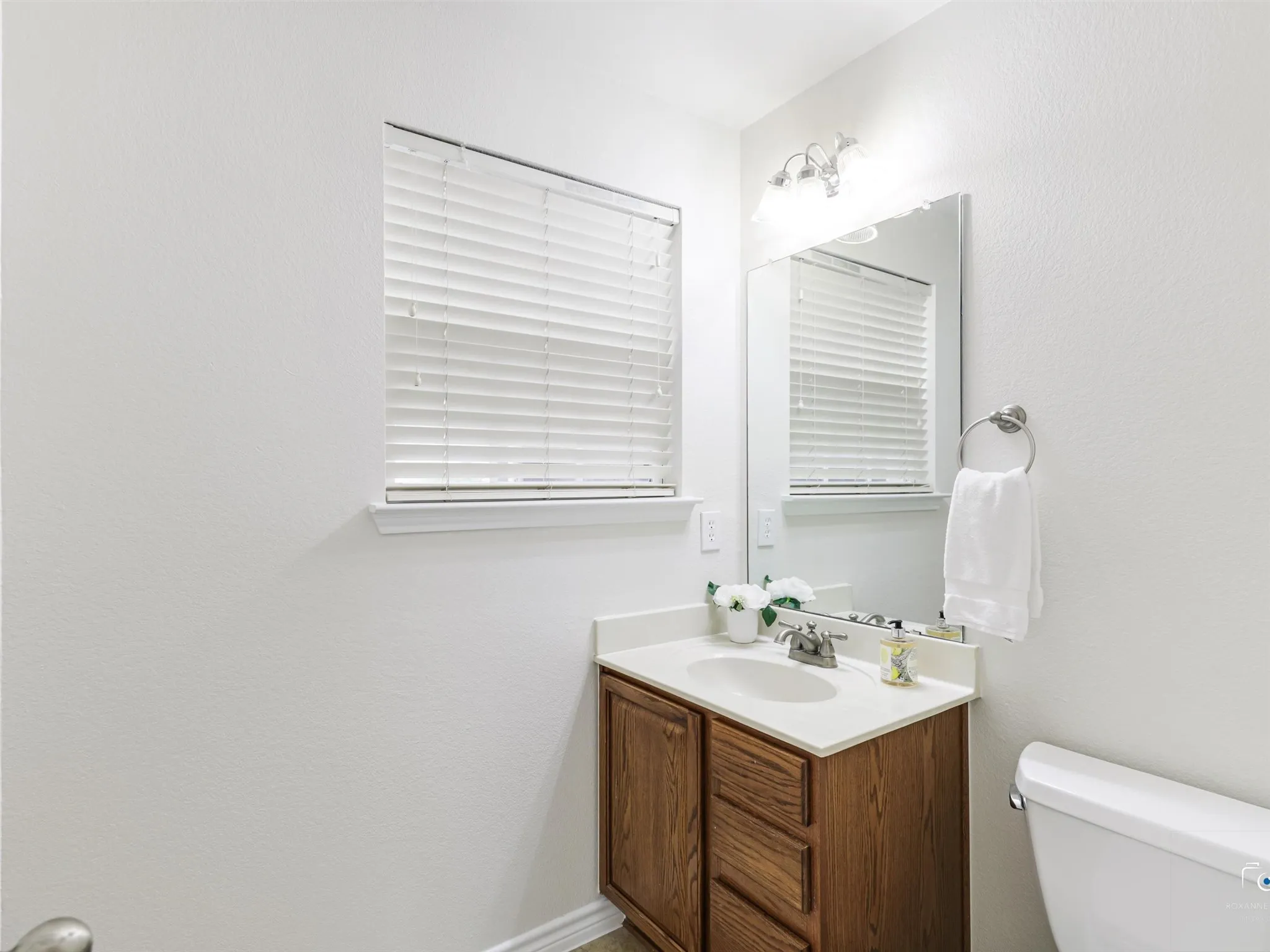 Bathroom with a wood-finish vanity, integrated sink, and light-toned countertop
