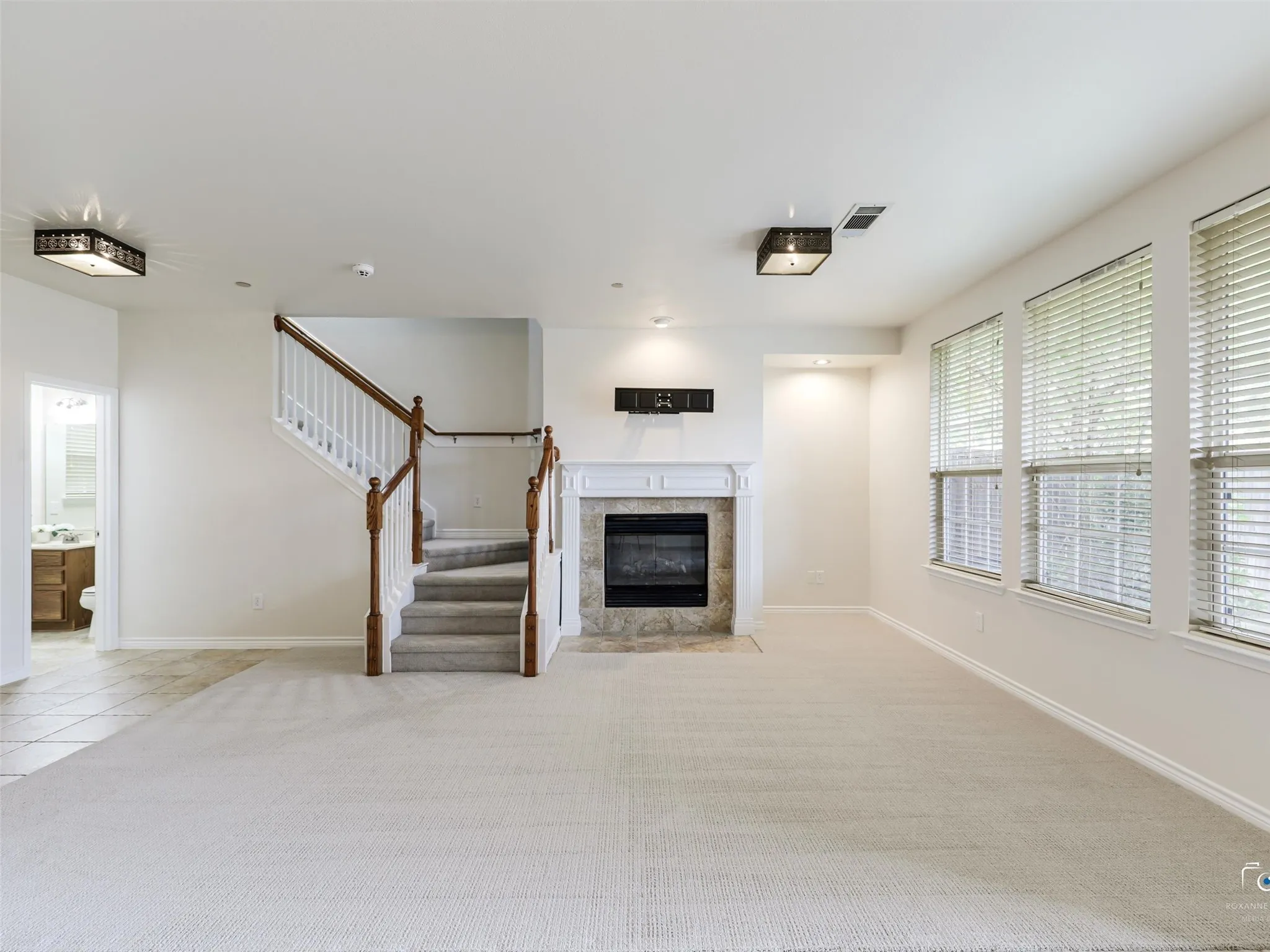 Spacious living area featuring light-toned carpeting and multiple windows