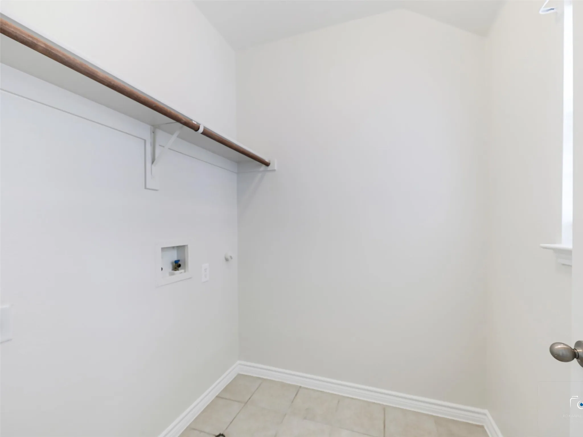 Dedicated utility space featuring a built-in shelf, clothing rod, and tile flooring