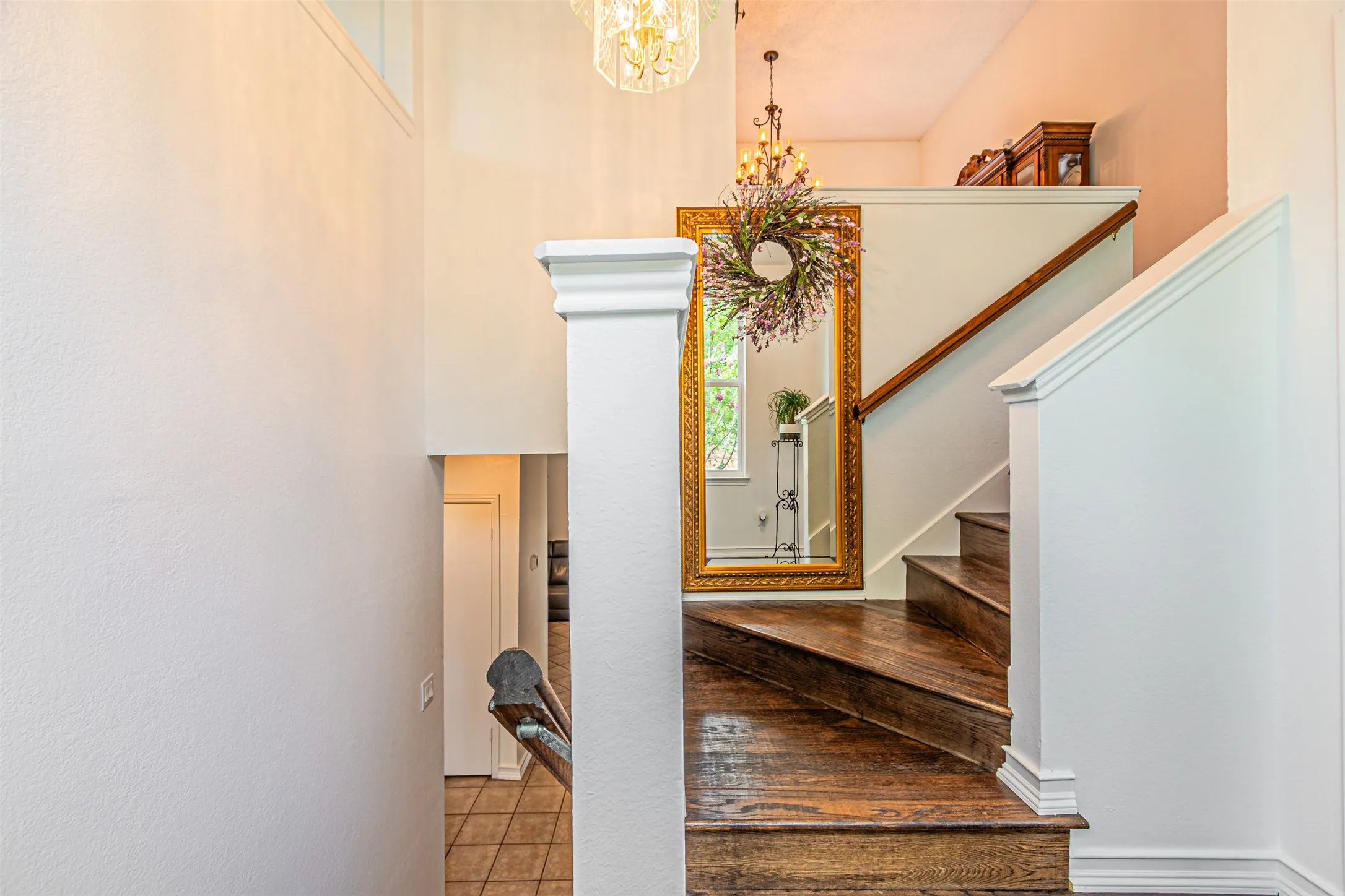Staircase featuring rich wood-finish treads and risers, a wood-finish handrail, white painted balustrade, and a decorative light fixture