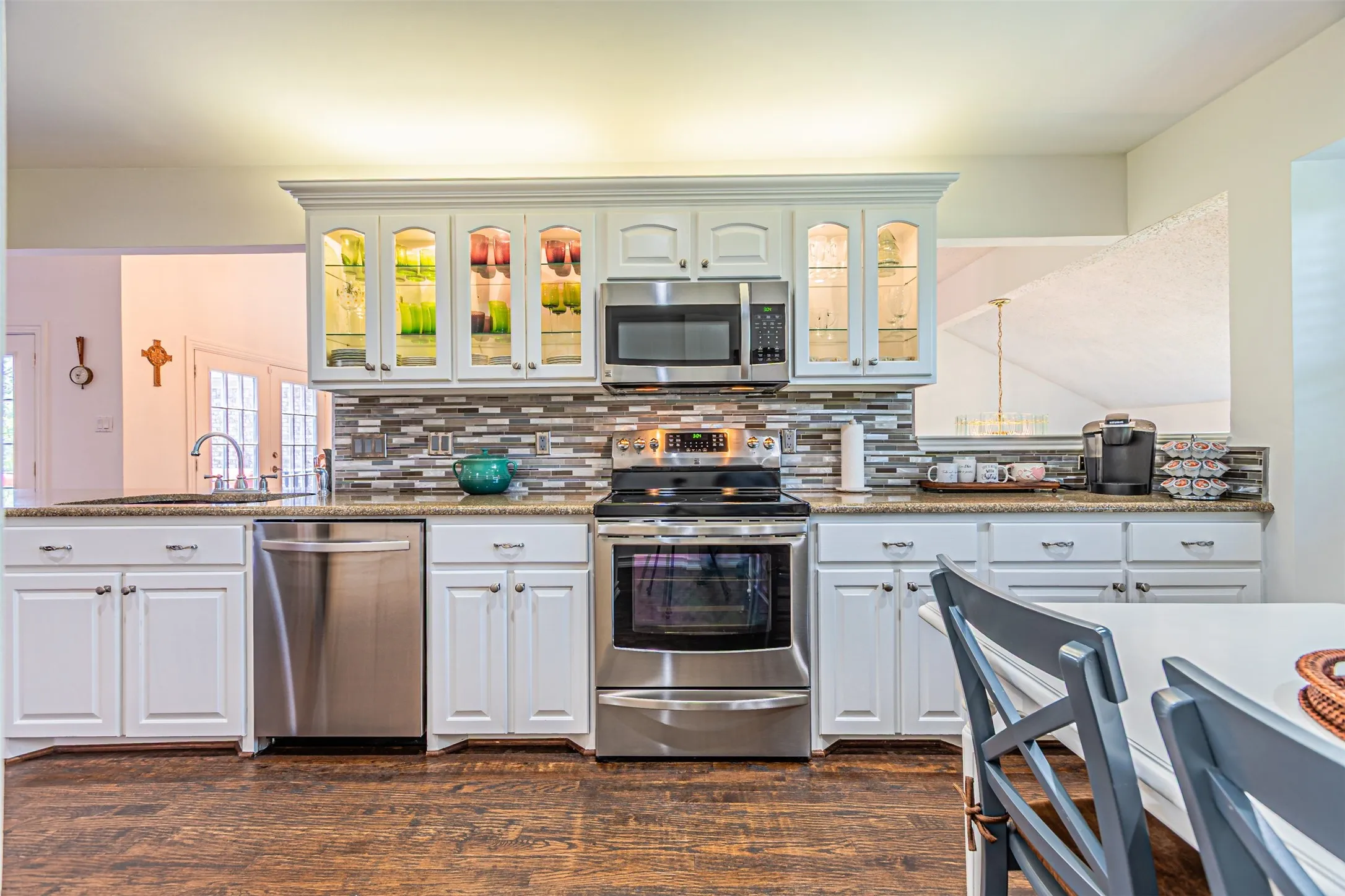 Kitchen featuring white cabinetry, stainless steel appliances, a mosaic tile backsplash, and wood-finish flooring