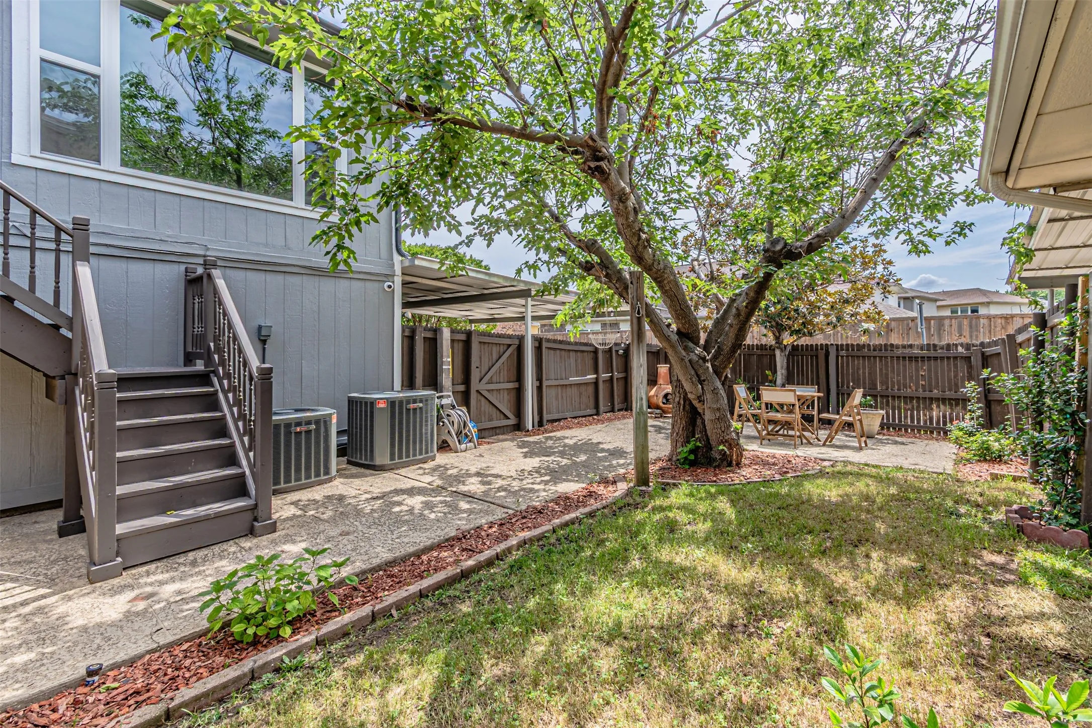 Private backyard featuring a mature shade tree, concrete patio, and fenced perimeter