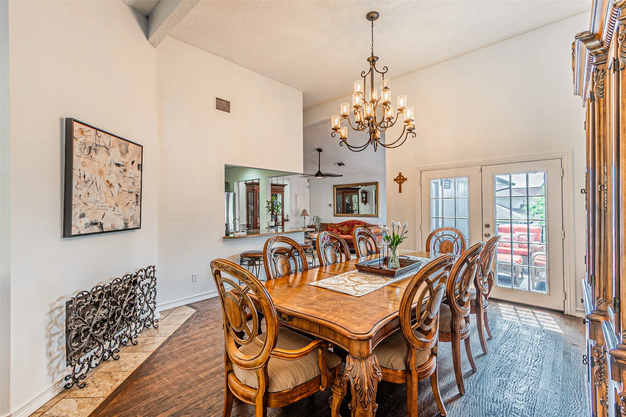 Dining area featuring high ceilings, wood-finish flooring, a decorative wrought-iron accent, and double French doors with transom windows