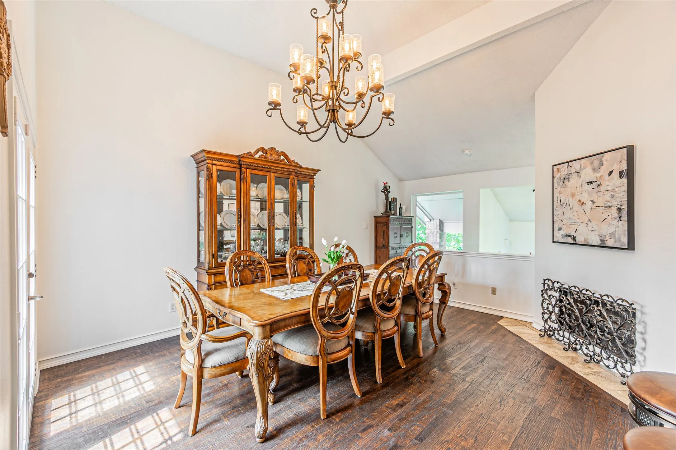 Spacious dining area featuring vaulted ceilings, a decorative wrought iron chandelier, and wood-finish flooring
