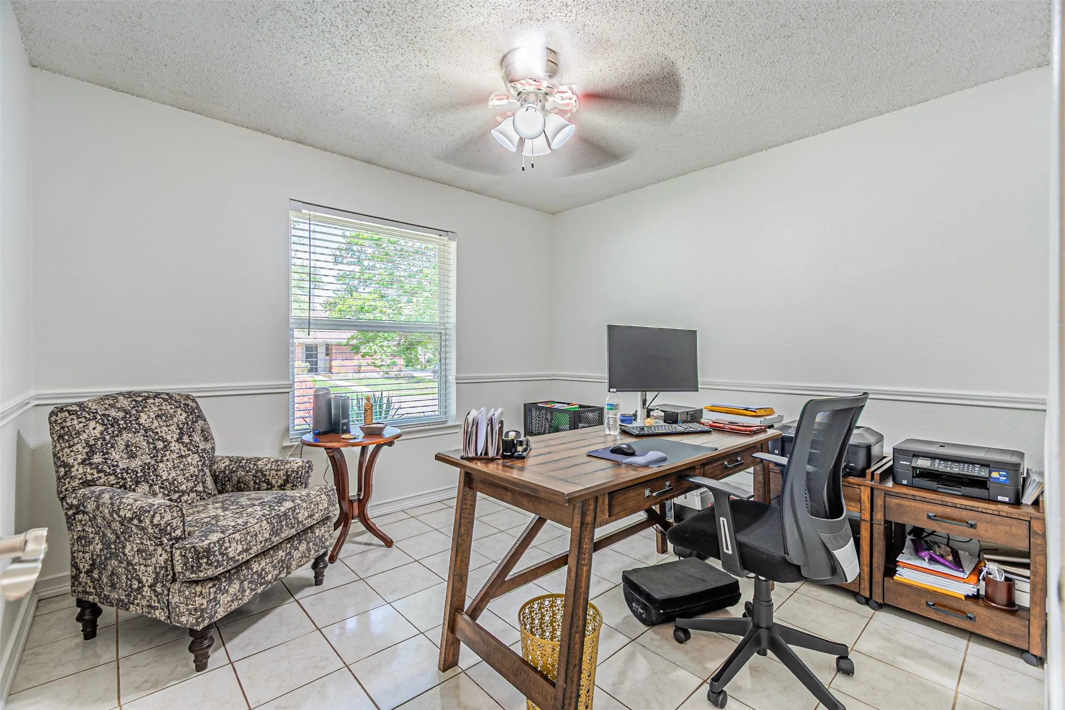 Spacious room featuring white tile flooring, white walls with chair rail molding, and a window with blinds