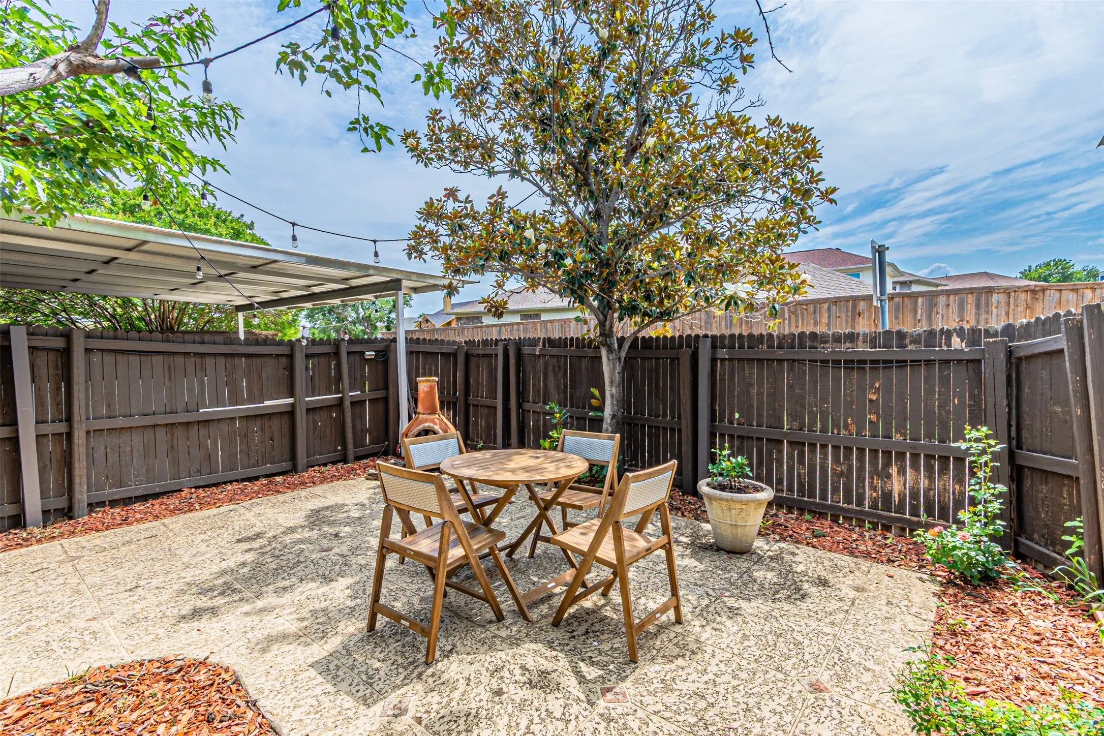Private backyard featuring a concrete patio, mature tree, and perimeter wood fencing