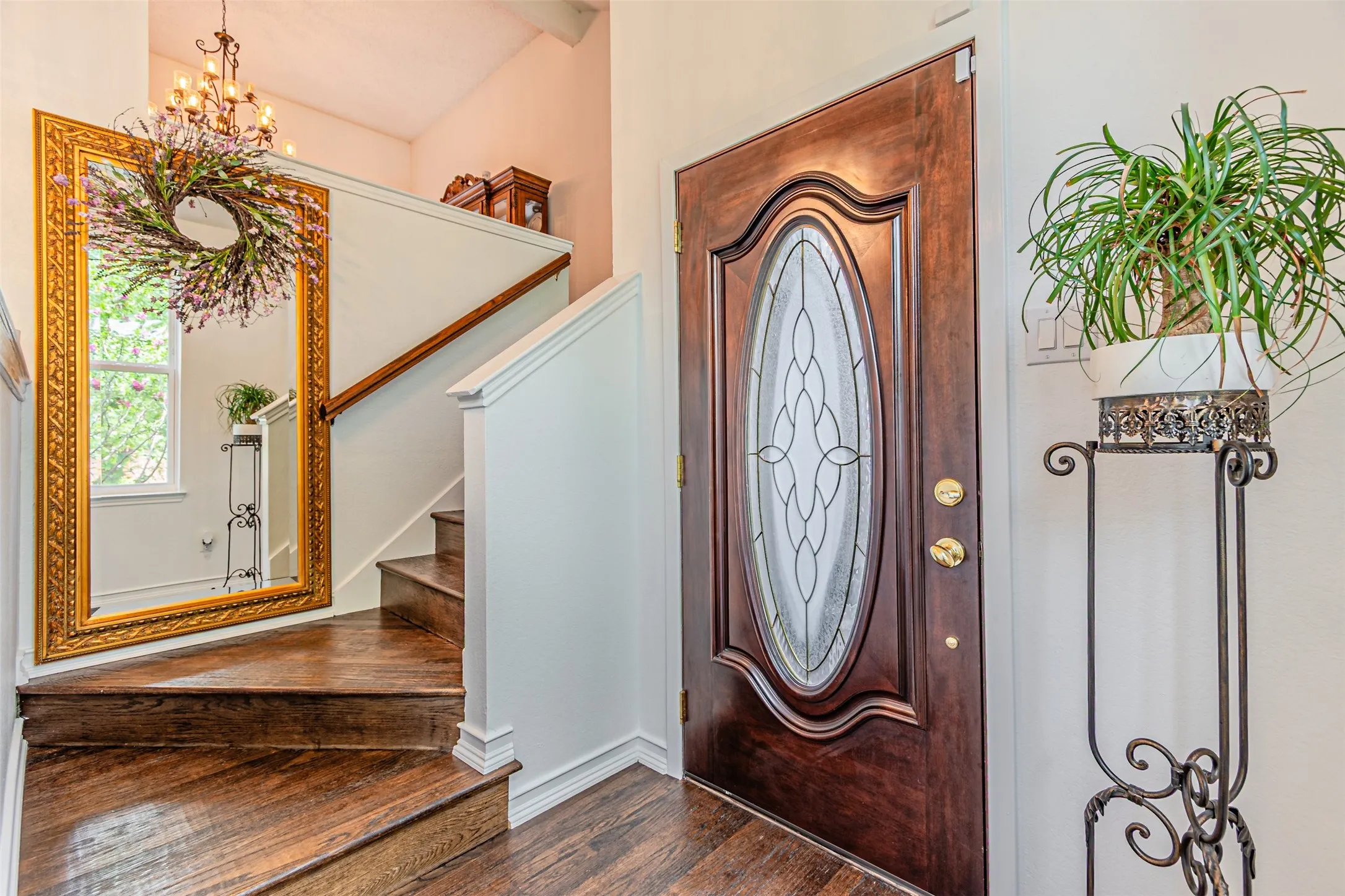 Entryway featuring a wood-panel door with oval leaded glass, dark wood-finish flooring, and a staircase with a wood handrail