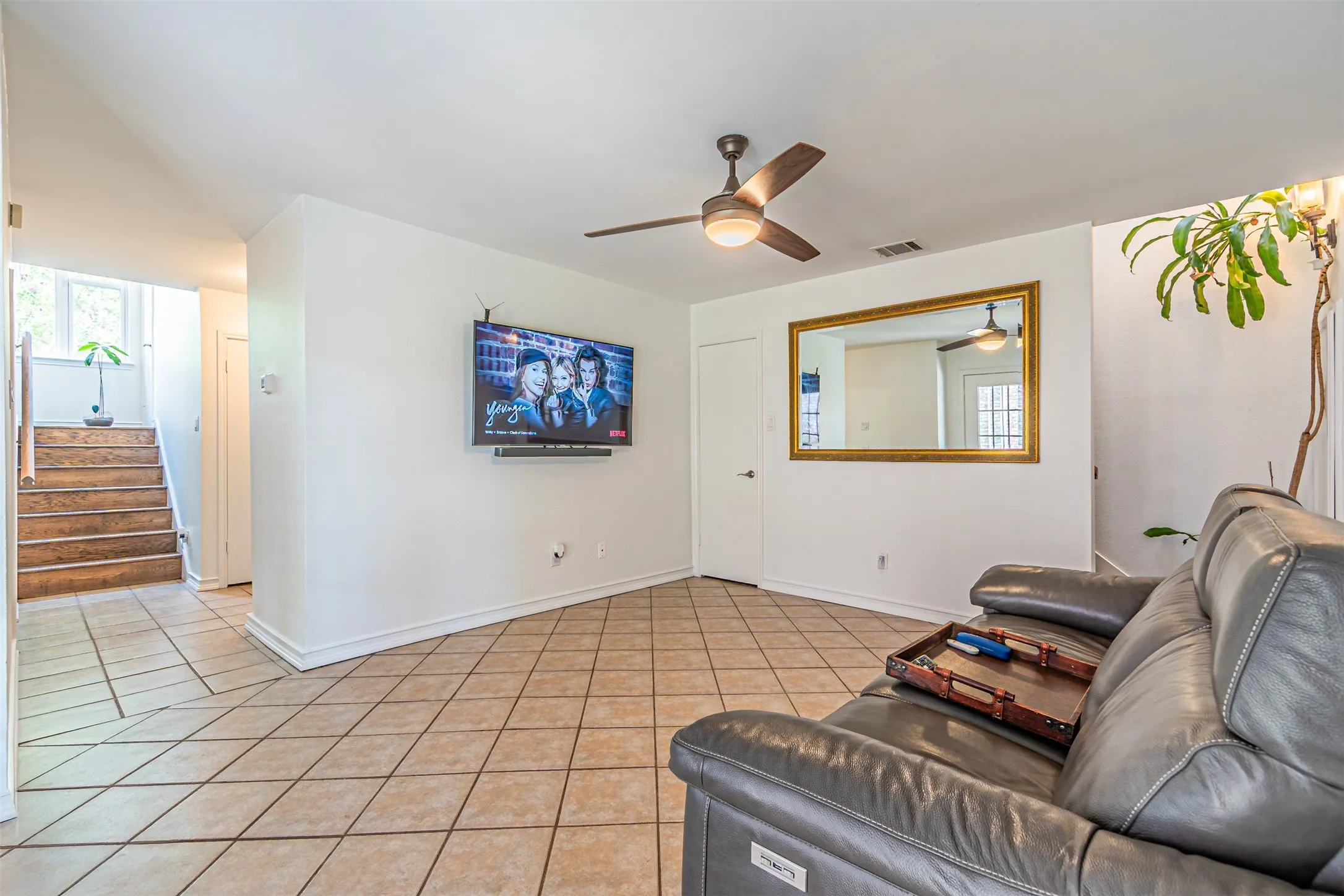 Spacious living area featuring neutral tile flooring, a contemporary ceiling fan, and white baseboards