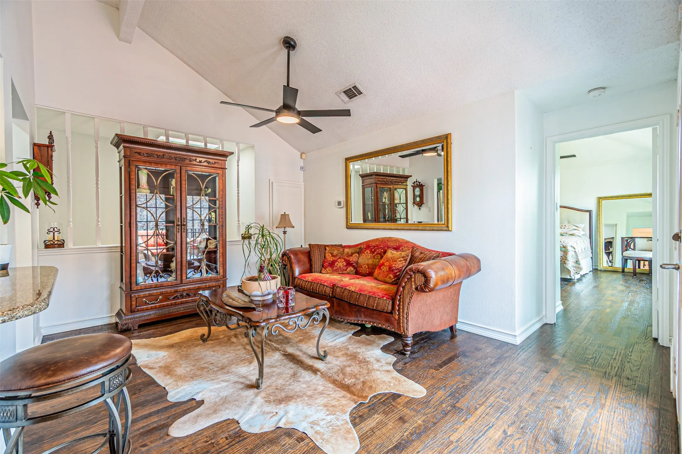 Living area with wood-finish flooring, vaulted ceiling, and a ceiling fan