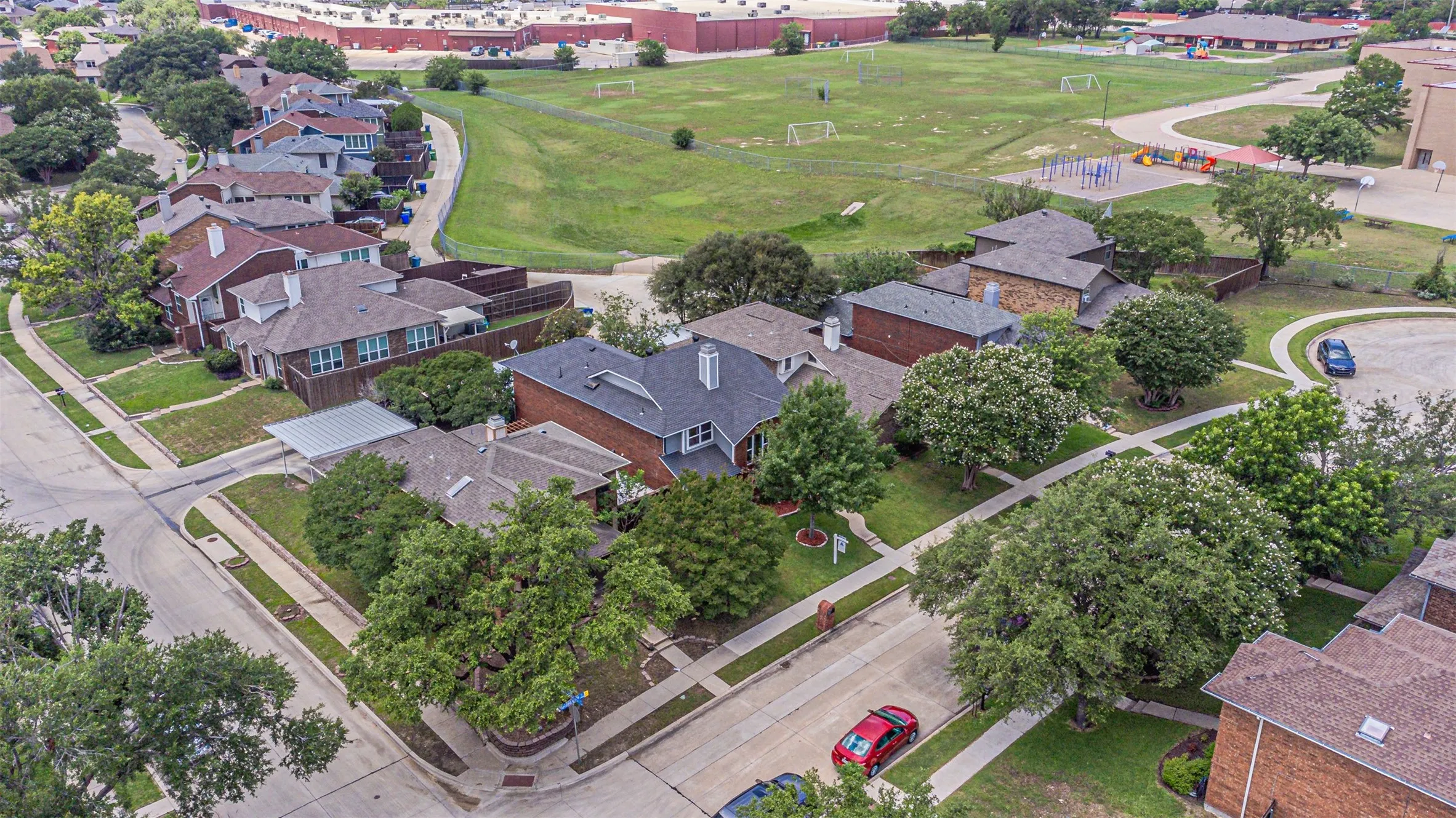 Aerial perspective showcasing a residential street with single-family homes and mature trees