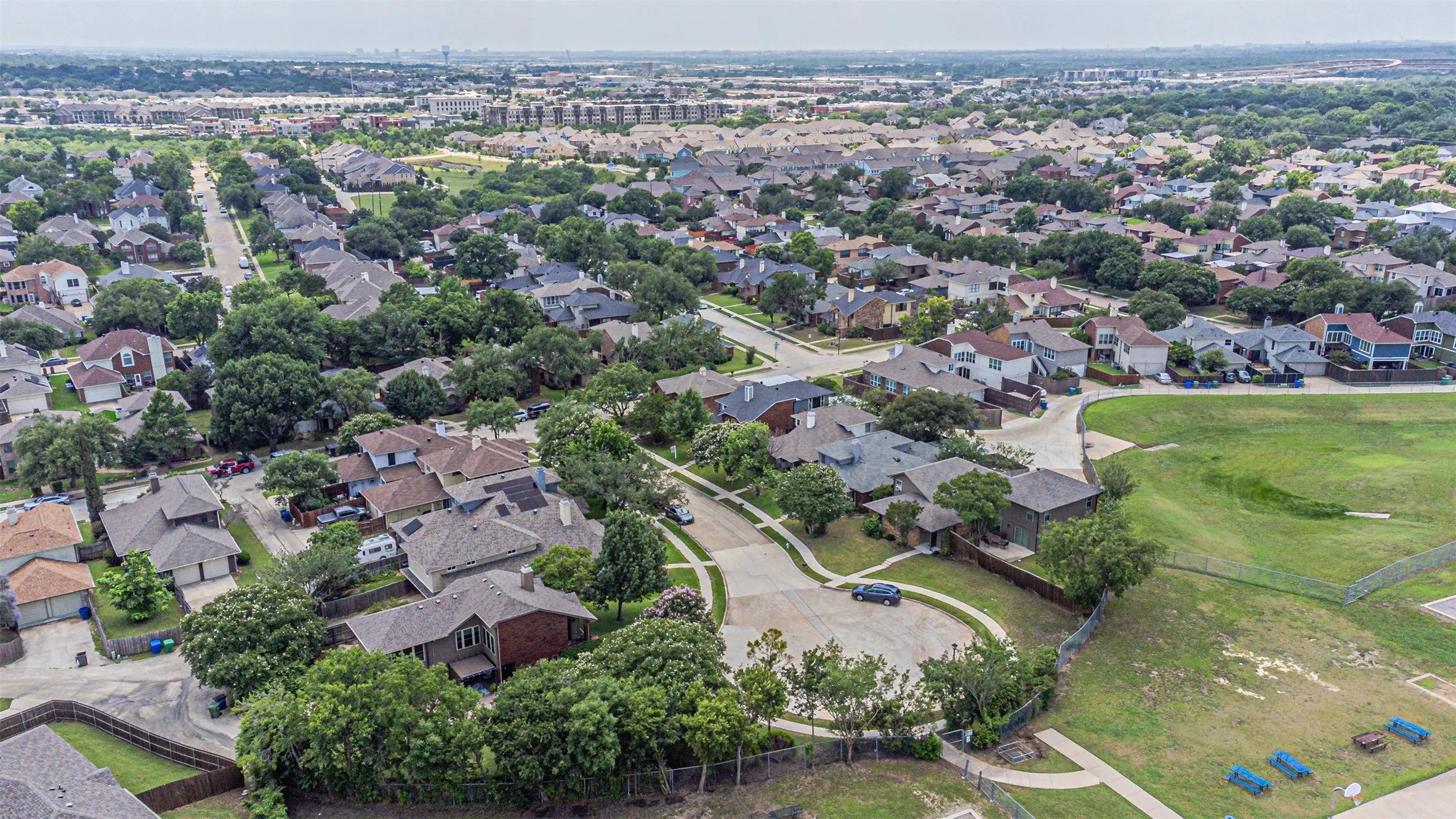 Aerial perspective showcasing a residential neighborhood with a mix of single-family homes, mature trees, and paved streets